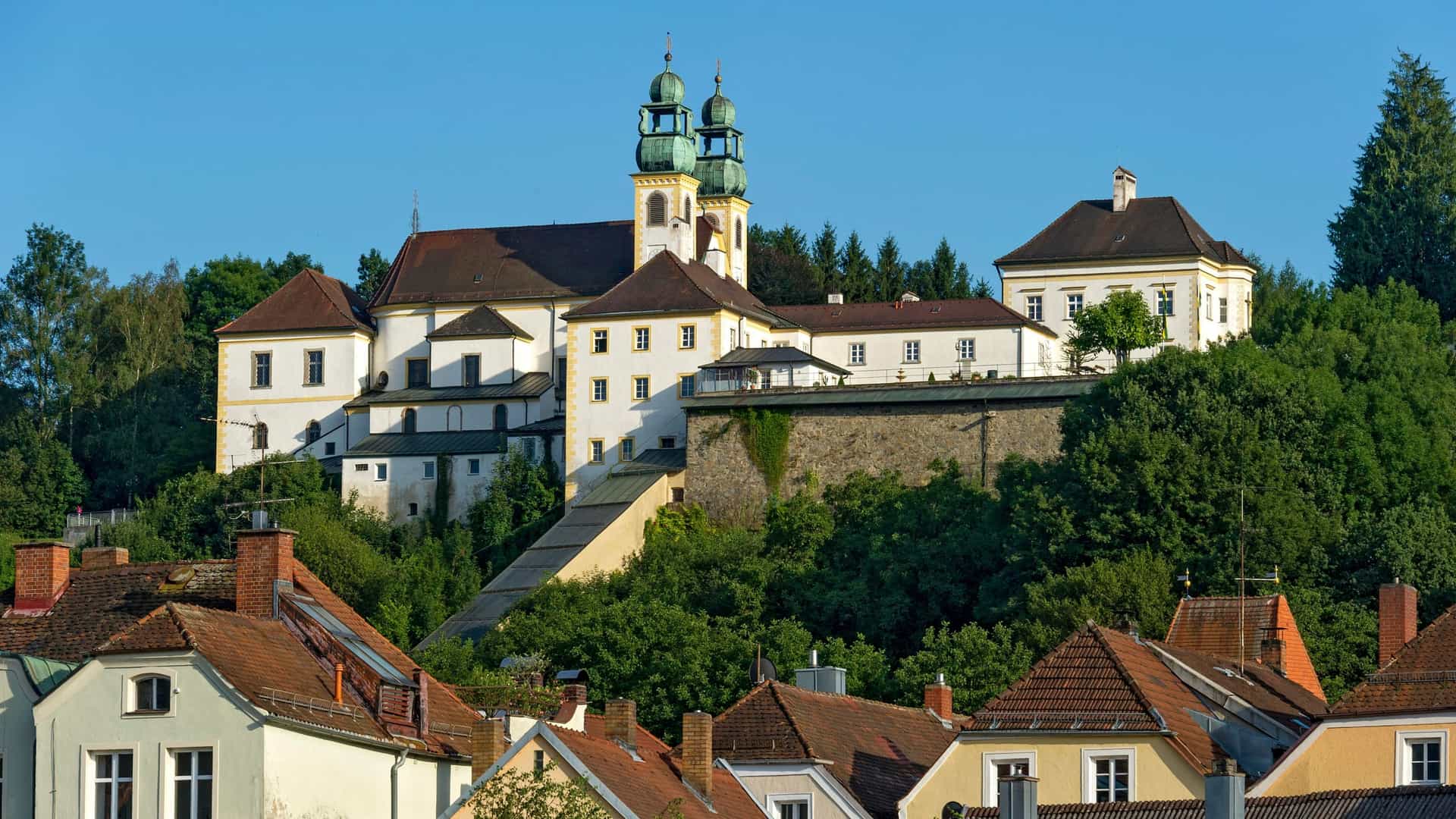 A view of the Mariahilf Pilgrimage Church and Monastery in Passau, Germany. The Baroque church and its towers are situated on a hill overlooking the city.