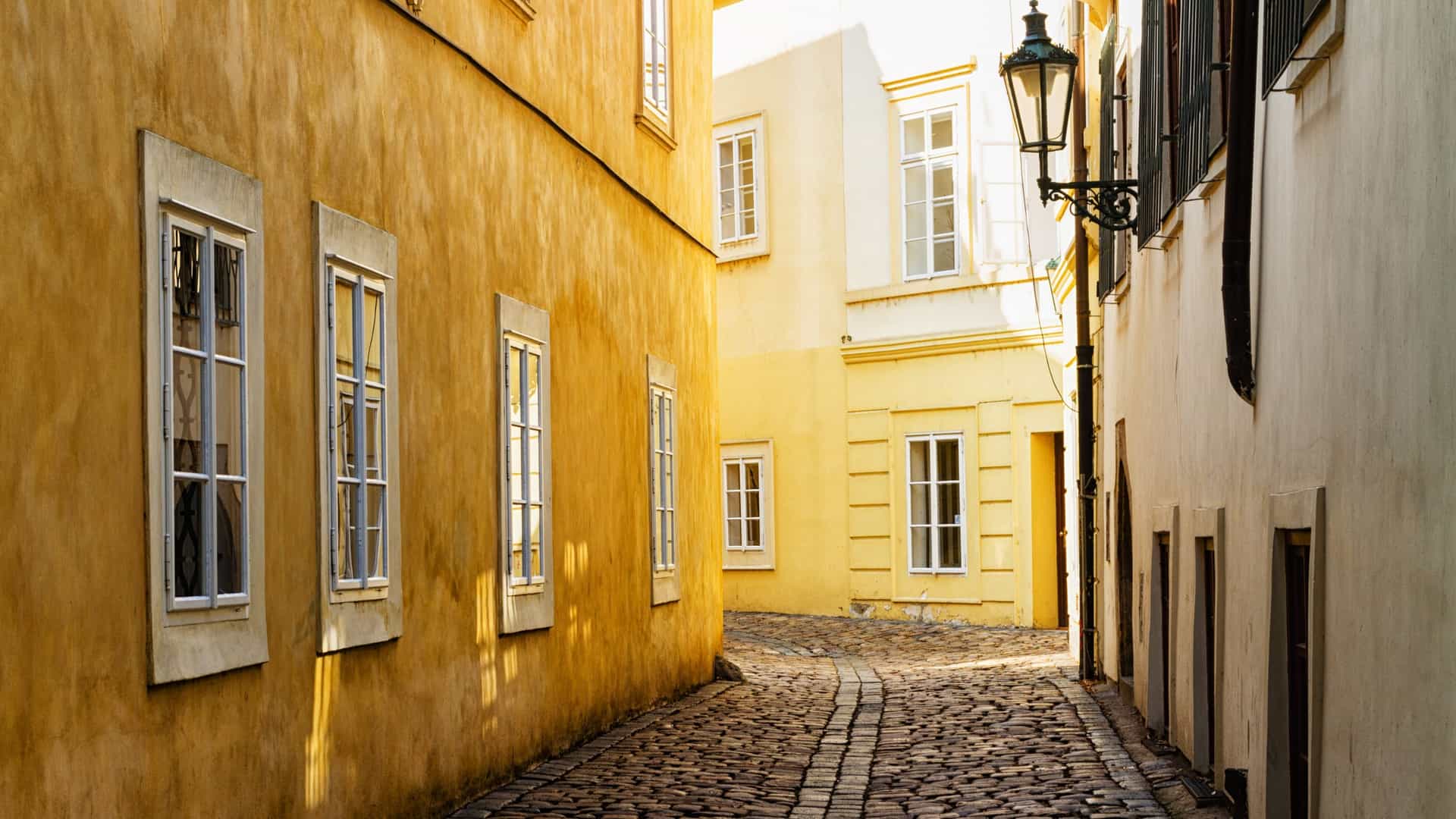 A close up view of a historic, ornate yellow apartment or tenement building on the corner of a street in Prague's Old Jewish Quarter (Josefov), Czech Republic, featuring classical or Art Nouveau architectural details.