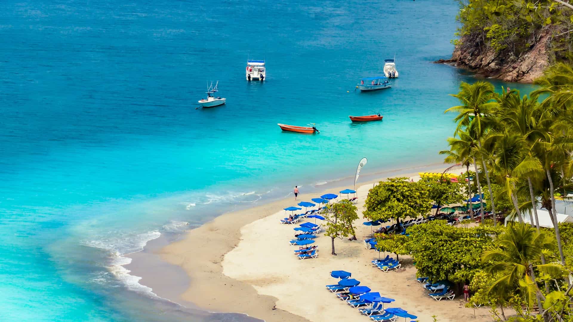 Aerial view of Tortuga Island, Costa Rica, showing a bright white sand beach, clear turquoise ocean water, and a lush forested hillside.