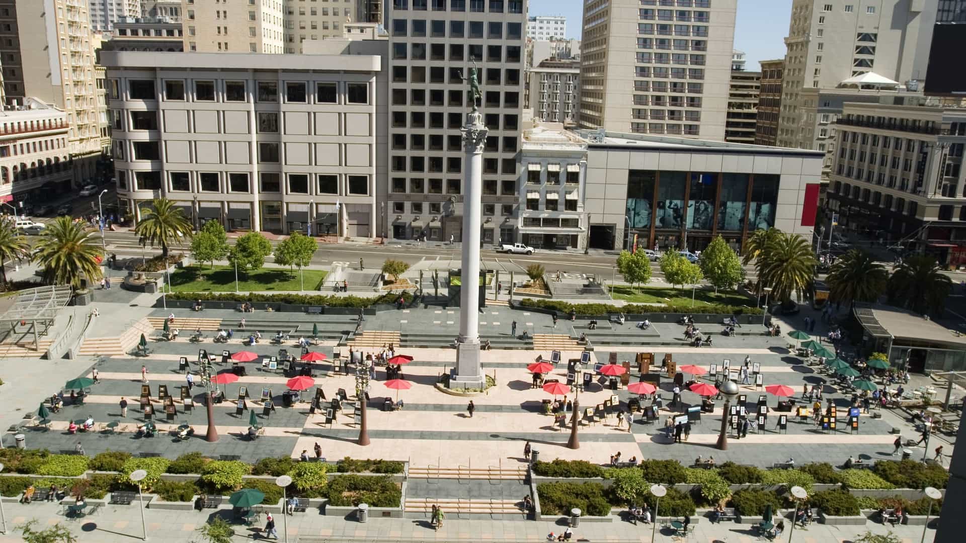 A bright, daytime view of San Francisco's Union Square, likely showcasing the Dewey Monument and the surrounding high end department stores and commercial buildings, with a focus on the bustling atmosphere that makes it a prime shopping destination. The scene may also include cable cars or pedestrian traffic in the foreground.