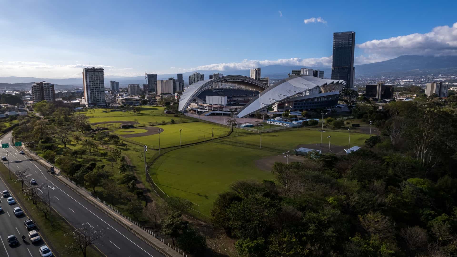 A beautiful aerial view of Metropolitan Central Park La Sabana in San José, Costa Rica. The large green urban park is visible, with a side view of the adjacent National Stadium in the background.