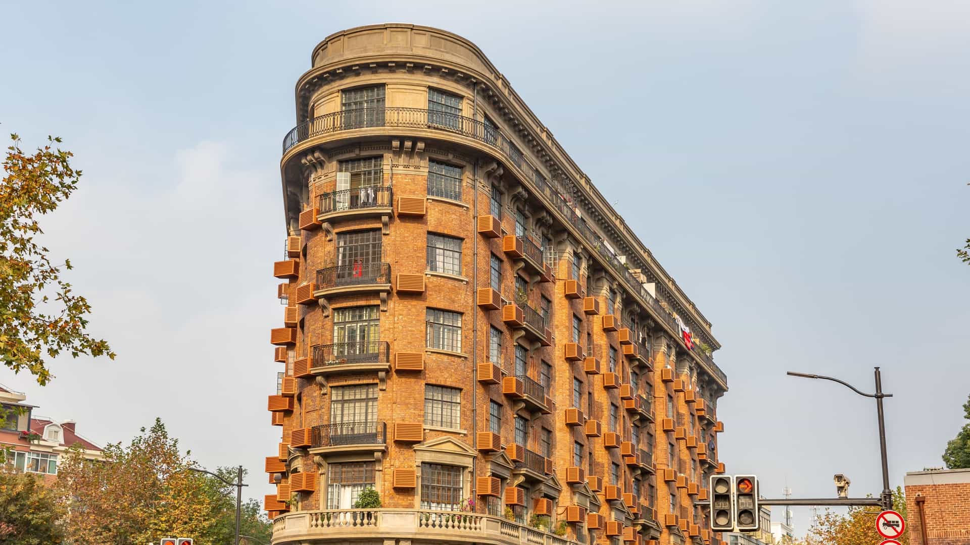 A tree lined street in the former French Concession of Shanghai, with historic, European style residential buildings featuring red tile roofs and detailed facades.