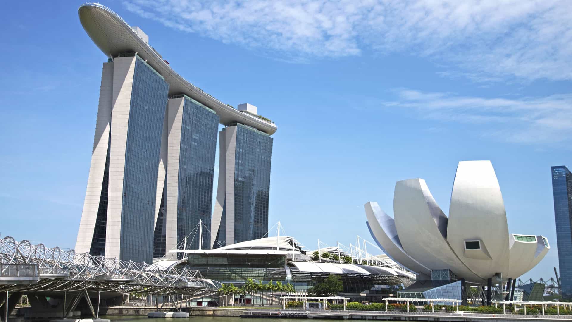 The iconic Marina Bay Sands integrated resort in Singapore, featuring three towering skyscrapers connected at the top by the boat shaped SkyPark, which houses the world famous Infinity Pool. The structure stands prominently against the city skyline and is often viewed with the surrounding Marina Bay and financial district buildings.