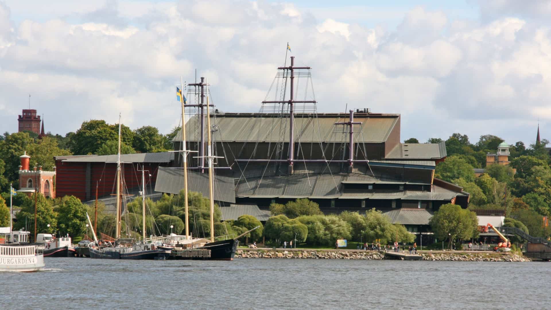 The exterior of the Vasa Museum (Vasamuseet) in Stockholm, Sweden, a modern building designed to house the 17th century warship Vasa. The museum is distinctive for its large copper colored roof and the three stylized masts extending from the roof, representing the height of the original ship's rigging.