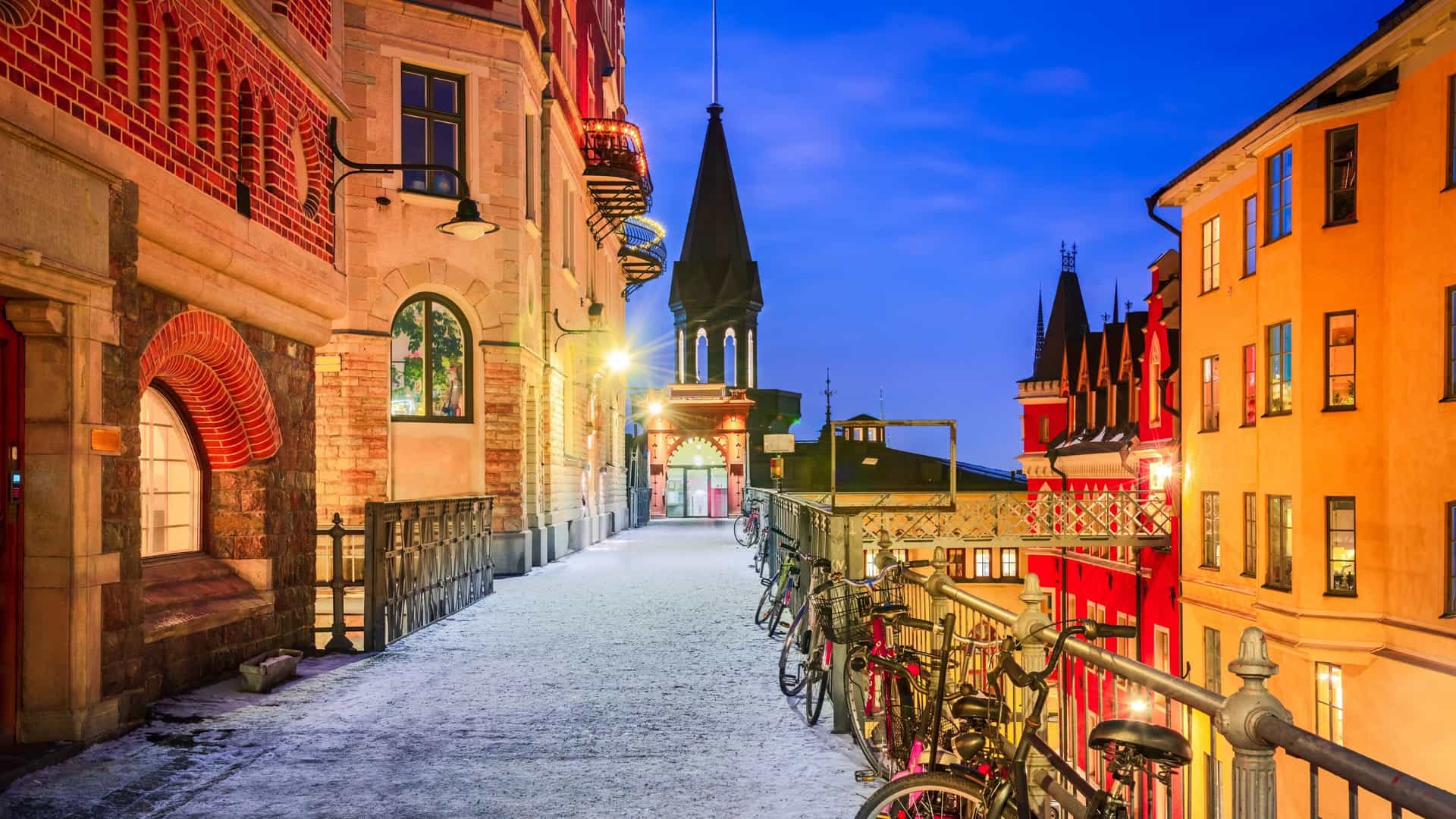 A view of Bellmansgatan, a picturesque, hilly street in Stockholm's Södermalm district. The street is paved with cobblestones and lined with classical, colorful Swedish buildings, creating an old town atmosphere.