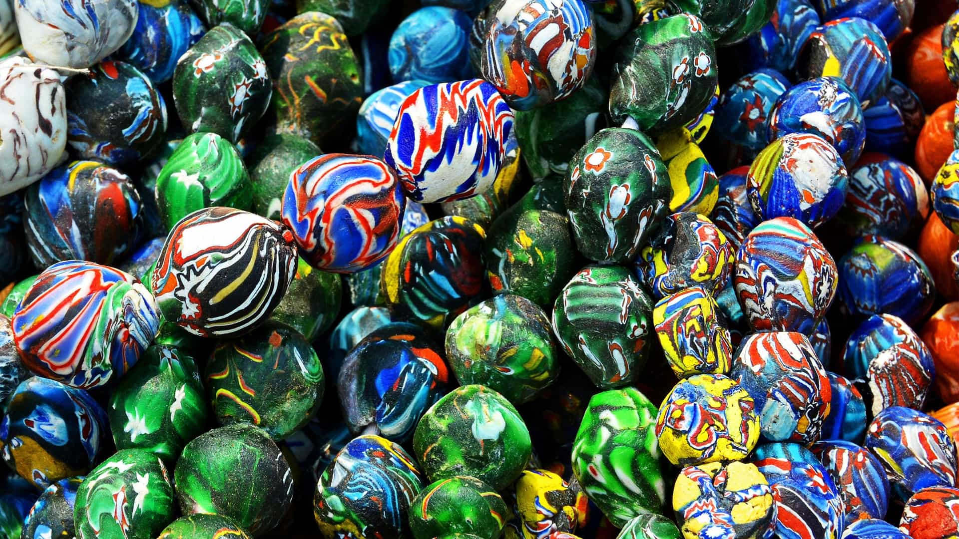 A close up photo showcasing a colorful display of unique, handmade beadwork jewelry for sale at a local craft market, likely in South Africa. The items include numerous beaded bracelets and bangles in vibrant patterns and colors, reflecting traditional African fashion and craftsmanship.