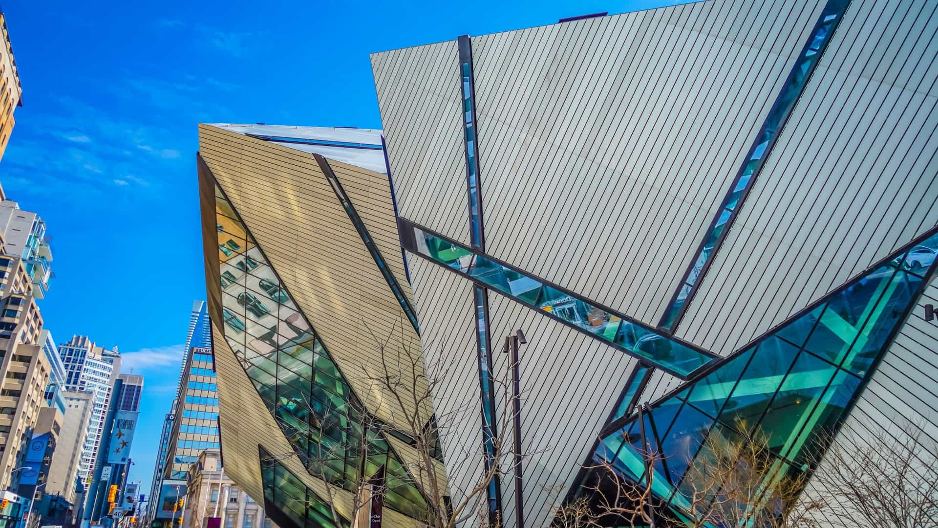 The Royal Ontario Museum (ROM) in Toronto, featuring the sharp, deconstructivist angles of the modern Michael Lee Chin Crystal extension, designed by Daniel Libeskind, dramatically jutting out from and contrasting with the museum's original, traditional heritage building.