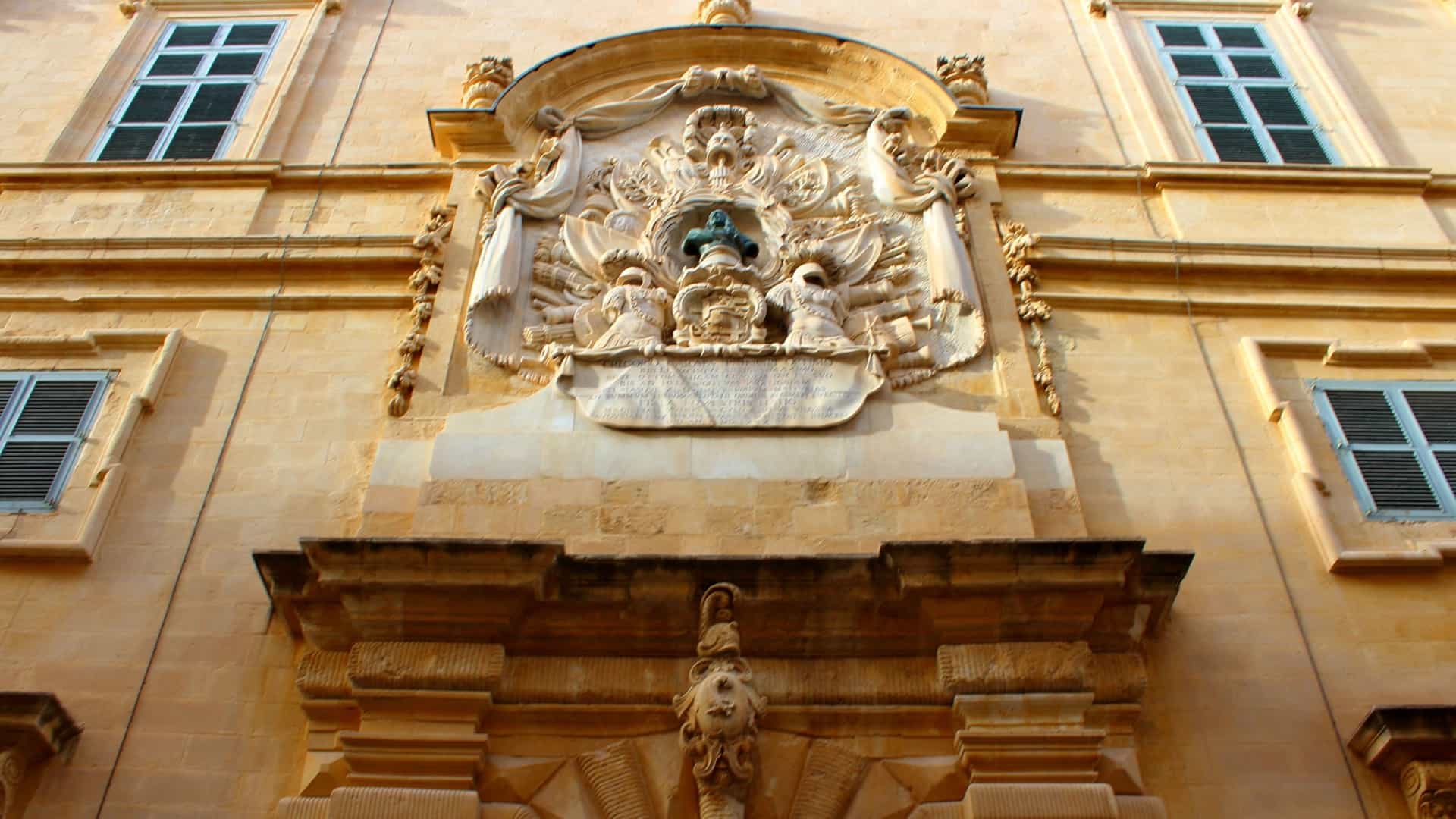 The Baroque facade of the National Museum of Archaeology, housed in the historic Auberge de Provence building on Republic Street in Valletta, Malta. The light colored limestone structure features ornate detailing and columns around the main entrance.