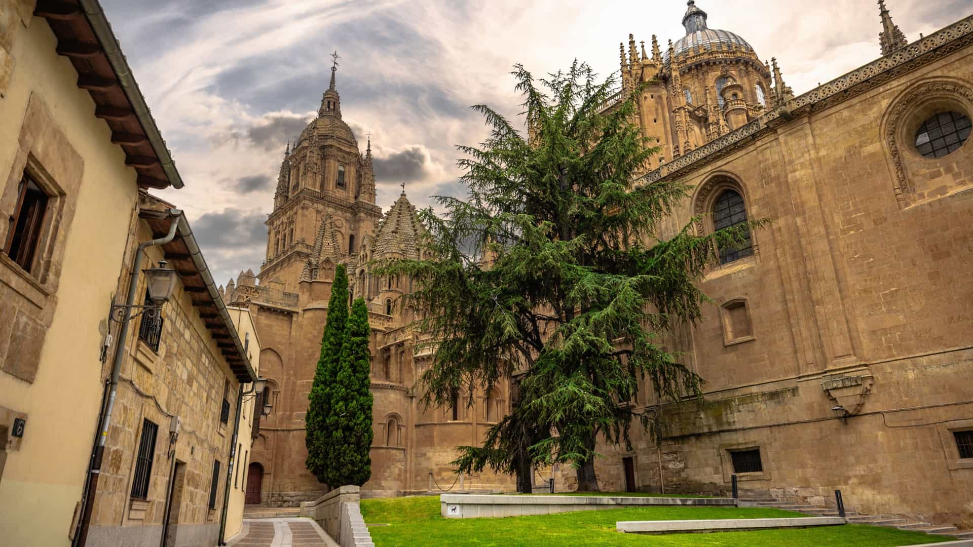 An elevated view of the historic Old Town of Salamanca, Spain, a UNESCO World Heritage site known as "La Ciudad Dorada" (The Golden City). The photo captures a dense collection of buildings constructed from golden Villamayor sandstone, including ornate facades, red tiled rooftops, and narrow streets. The architecture showcases a mix of Romanesque, Gothic, and Baroque styles.