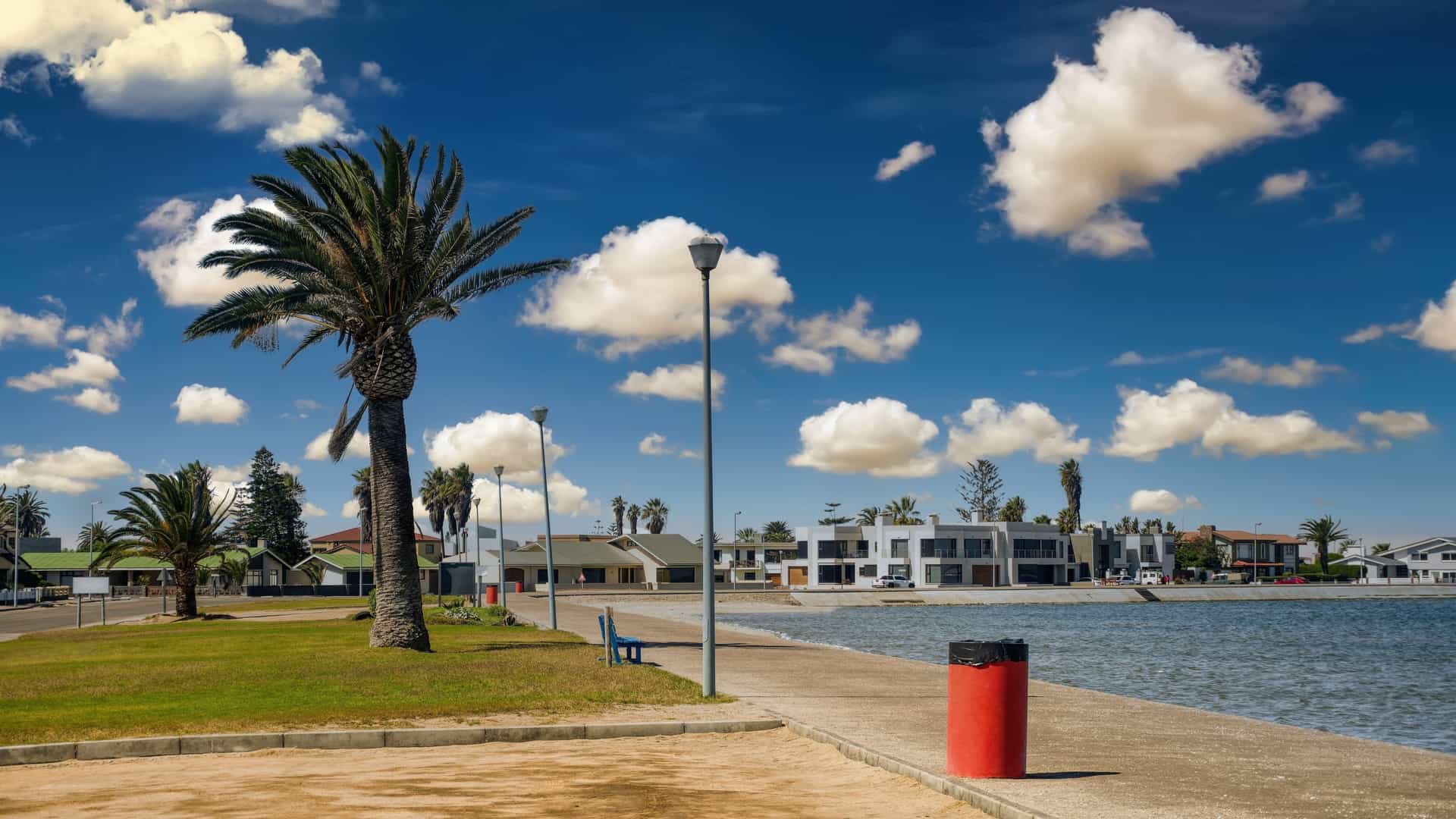 A row of modern, upmarket holiday homes with contemporary architecture along a waterfront or lagoon in Walvis Bay, Namibia, under a clear sky.