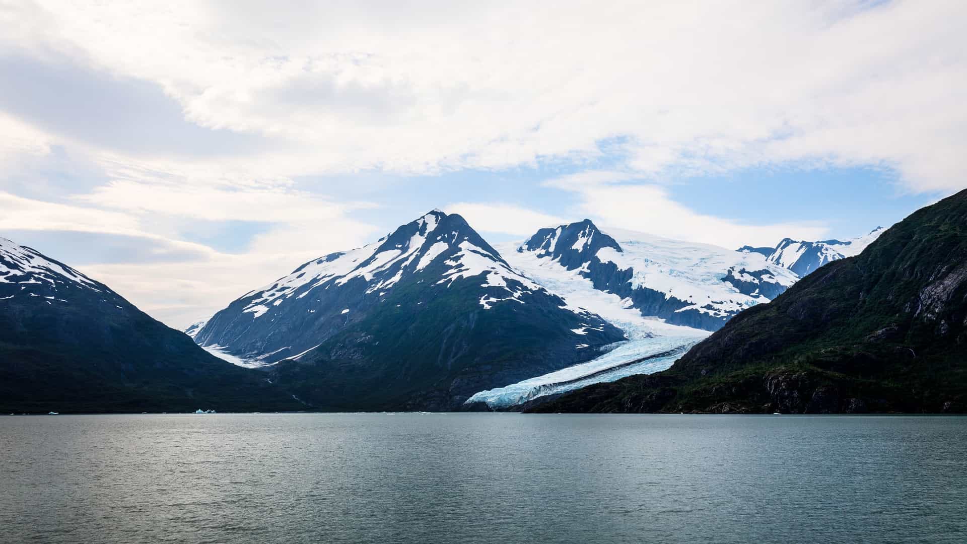 The Begich, Boggs Visitor Center stands on the shore of Portage Lake in the Chugach National Forest, Alaska. The modern, low profile building, constructed on the terminal moraine of the former Portage Glacier, features large windows and a distinct roofline. It overlooks the iceberg dotted lake, with a spectacular backdrop of steep, snow dusted Alaskan mountains.
