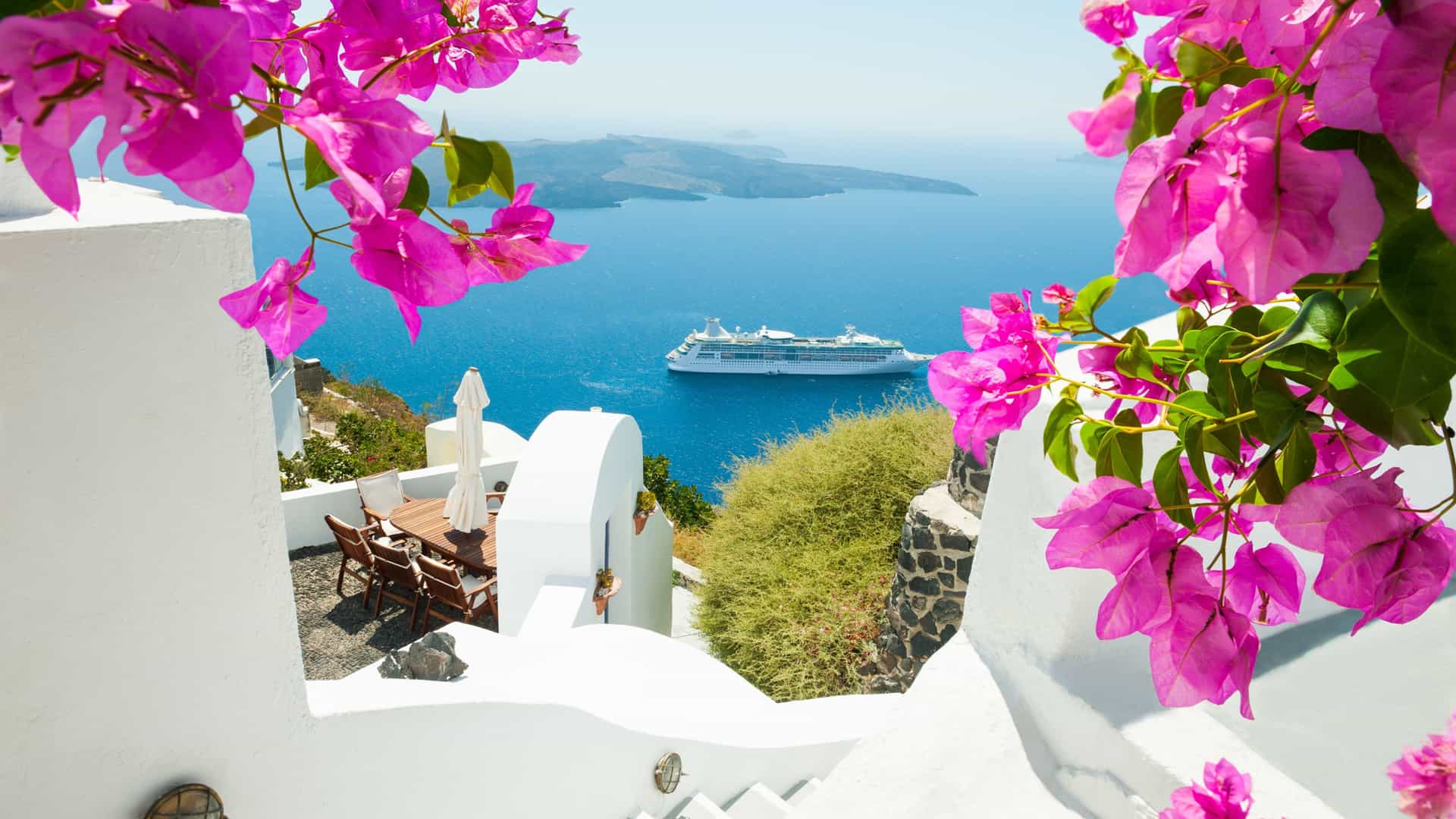White architecture on Santorini island, Greece with a cruise ship in the background.