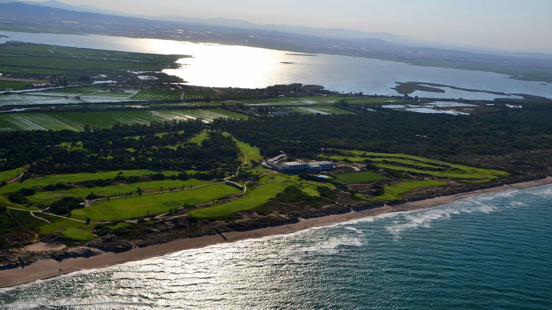 Aerial view of El Saler golf course in Valencia, Spain, showcasing coastal fairways running along a sandy Mediterranean beach and the Albufera Natural Park.