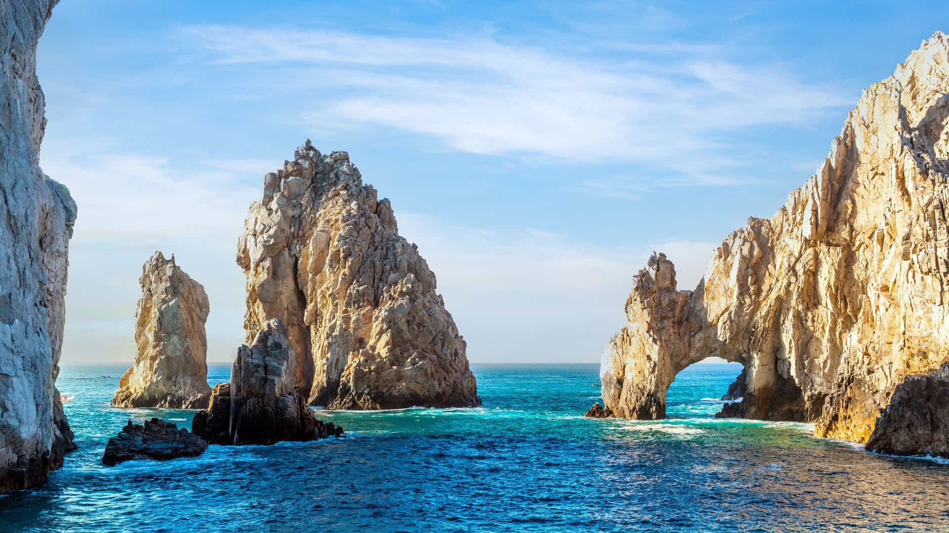 Holland America cruise ship near El Arco (Arch of Cabo San Lucas) in Cabo San Lucas, Mexico, rising from the Sea of Cortez off Baja California under a clear blue sky.