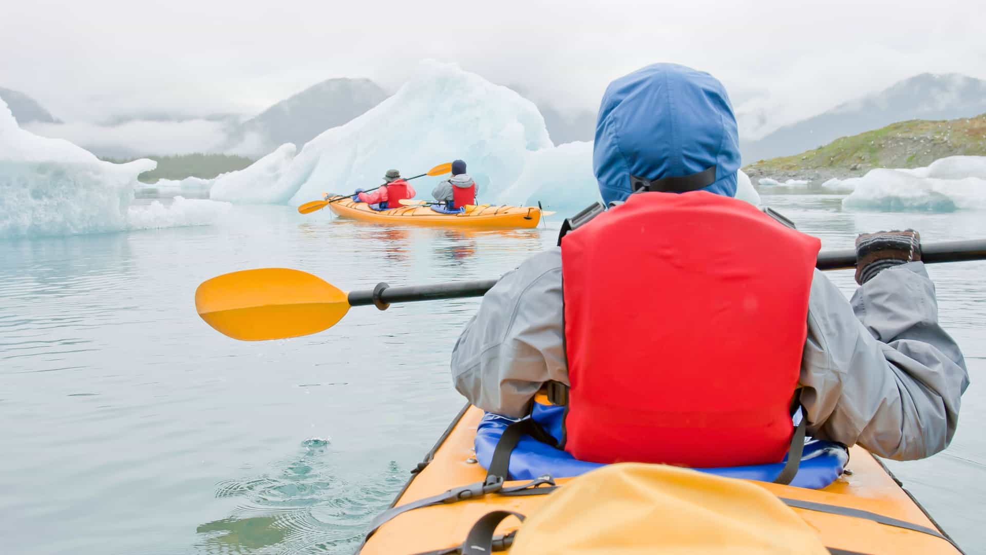3 people kayaking in Alaska.