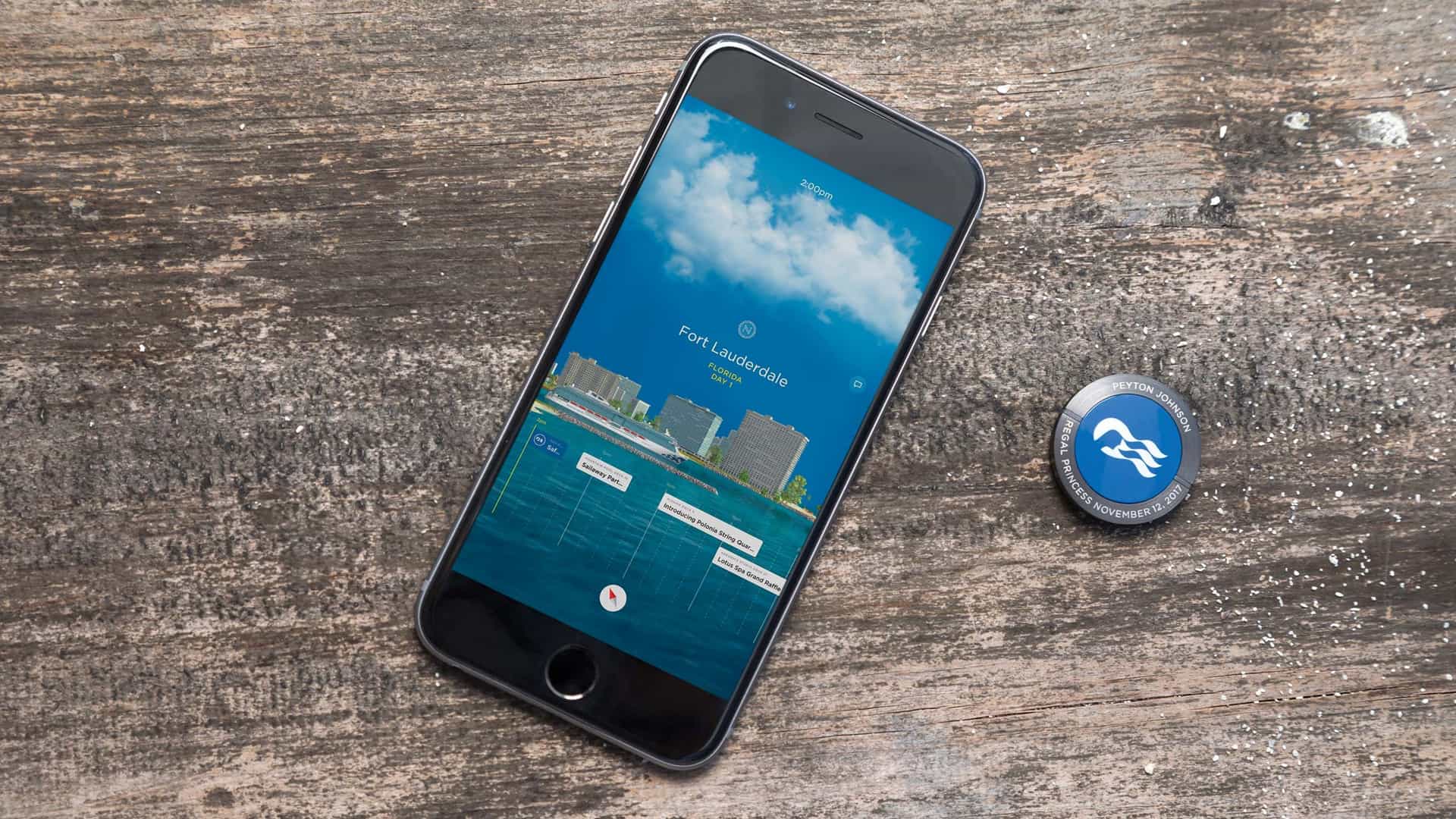 A birds-eye-view of an iPhone and a Princess Cruises Medallion laid flat on a wooden table.