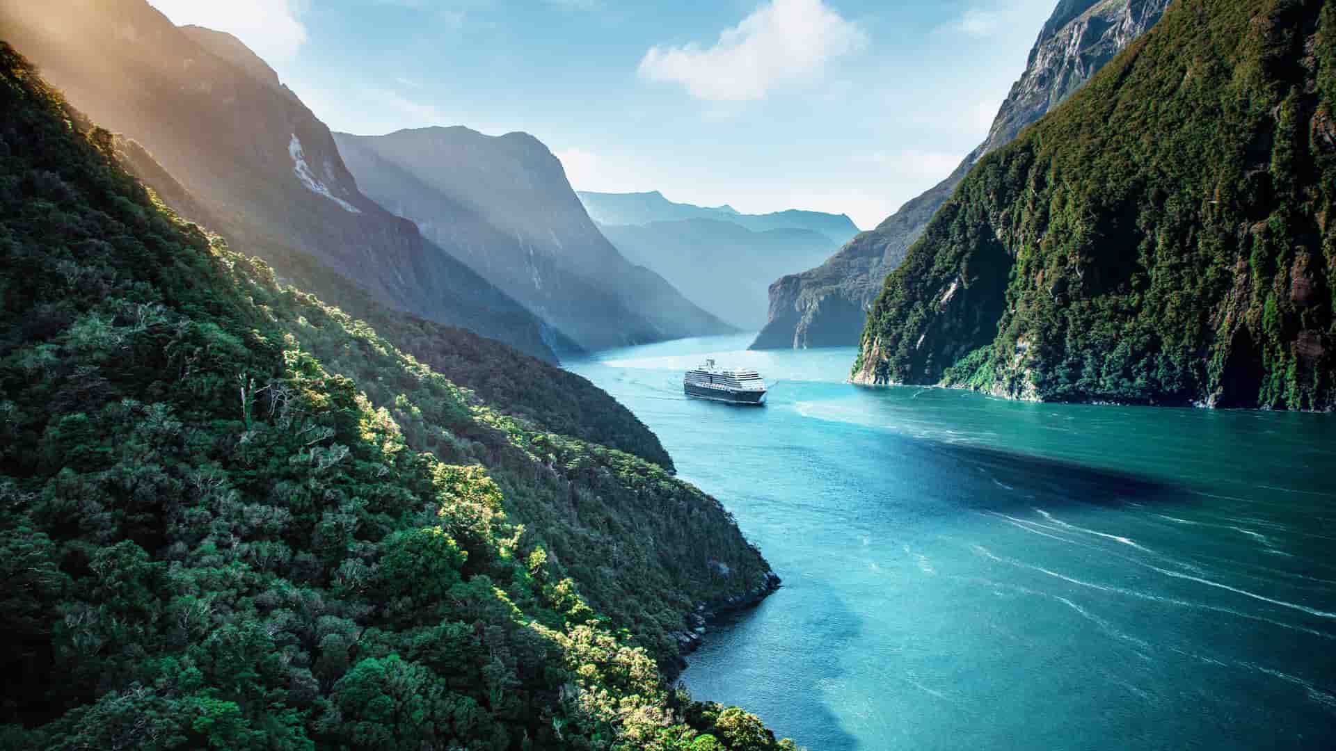 A mid-sized Holland America Line ship cruising through the Milford sound in New Zealand.