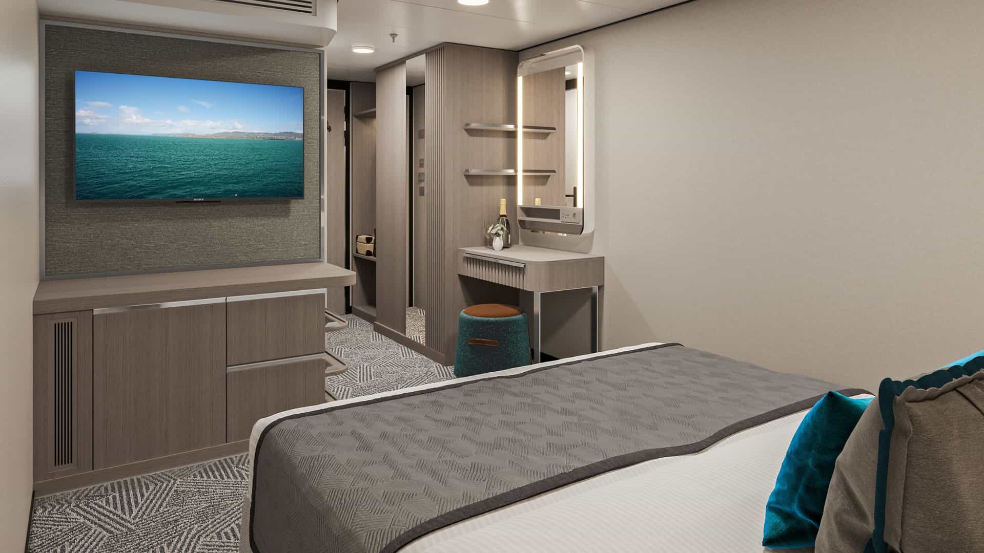 Modern inside stateroom on Norwegian Aqua featuring a comfortable bed, wall-mounted television, vanity desk with illuminated mirror and sleek wood cabinetry.