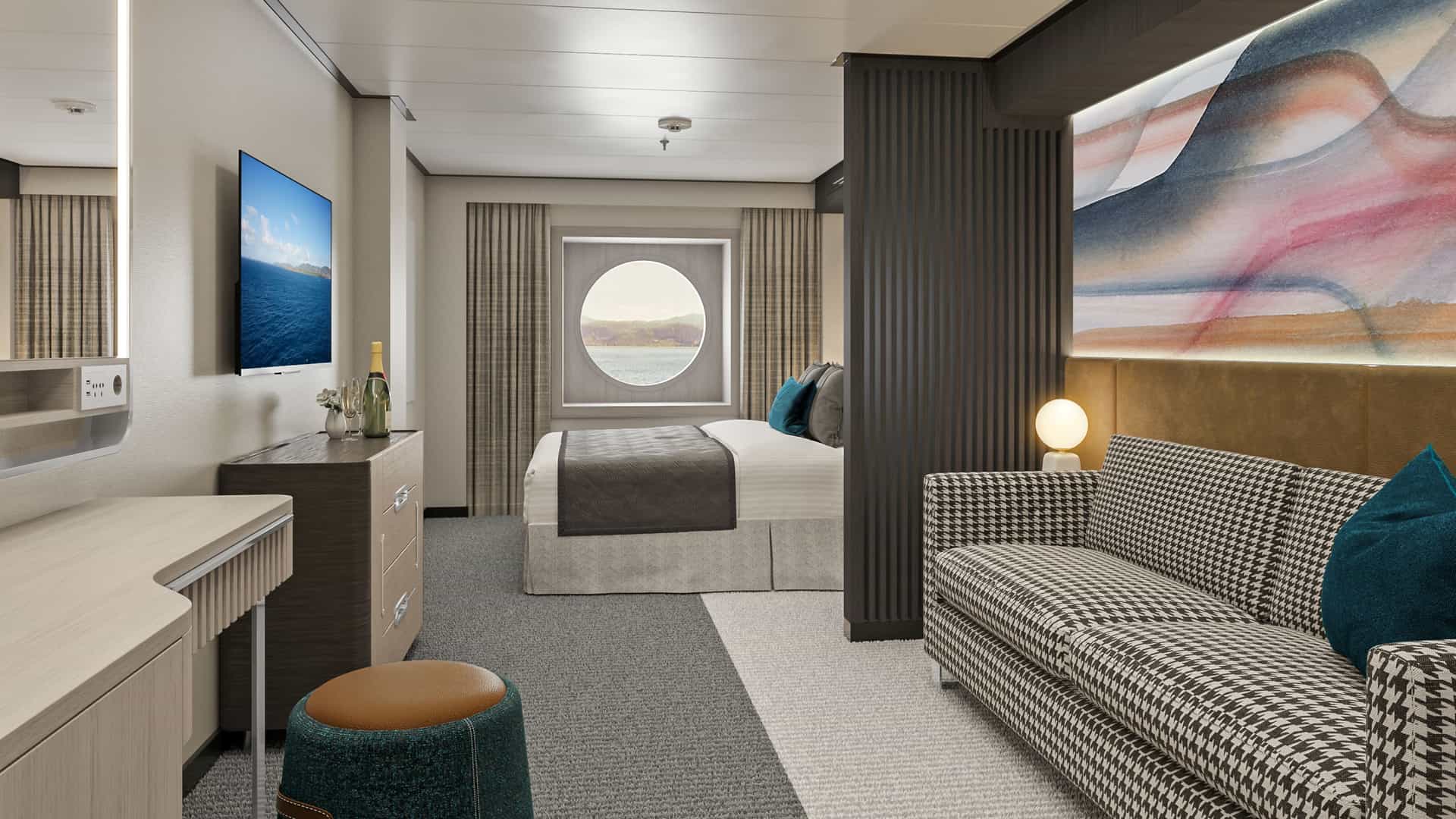 Modern oceanview stateroom on Norwegian Aqua featuring a round porthole window, double bed, patterned sofa and vanity desk area.