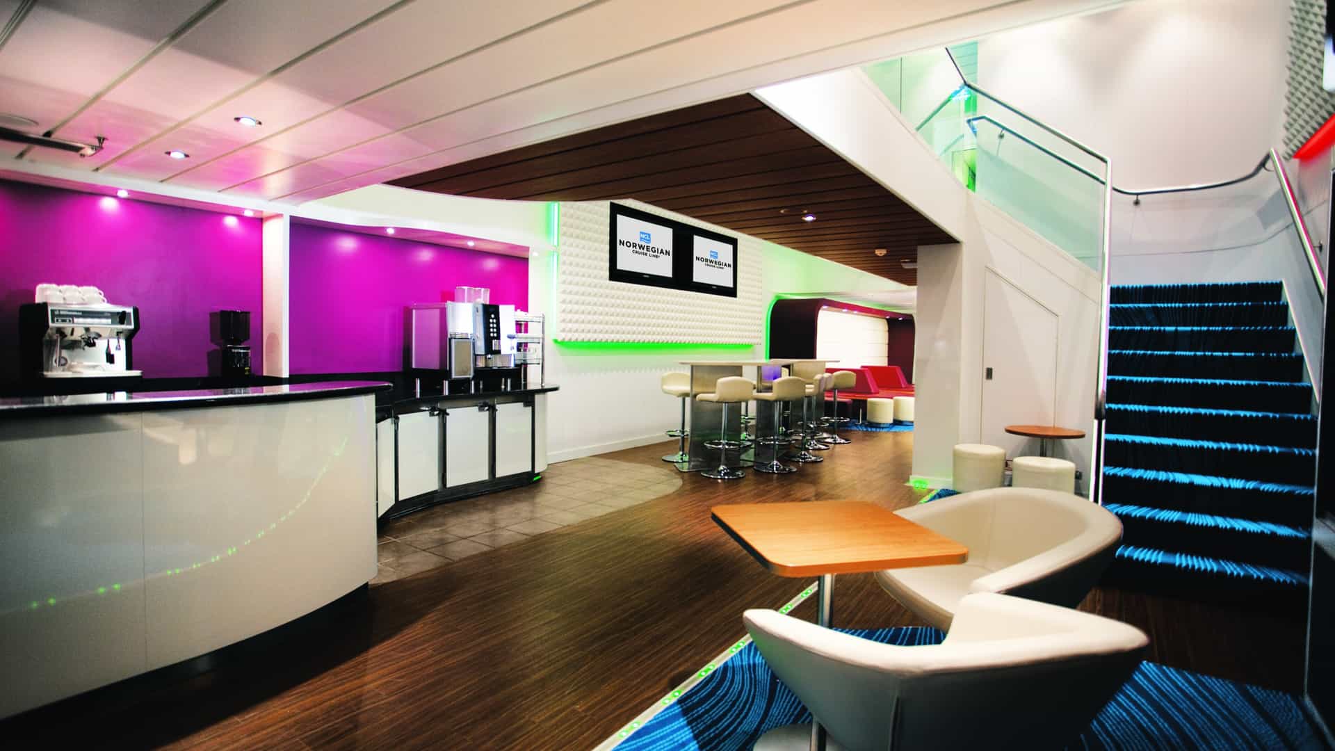 Studio Lounge on Norwegian Epic with a coffee counter, bar stools, white armchairs and a staircase.