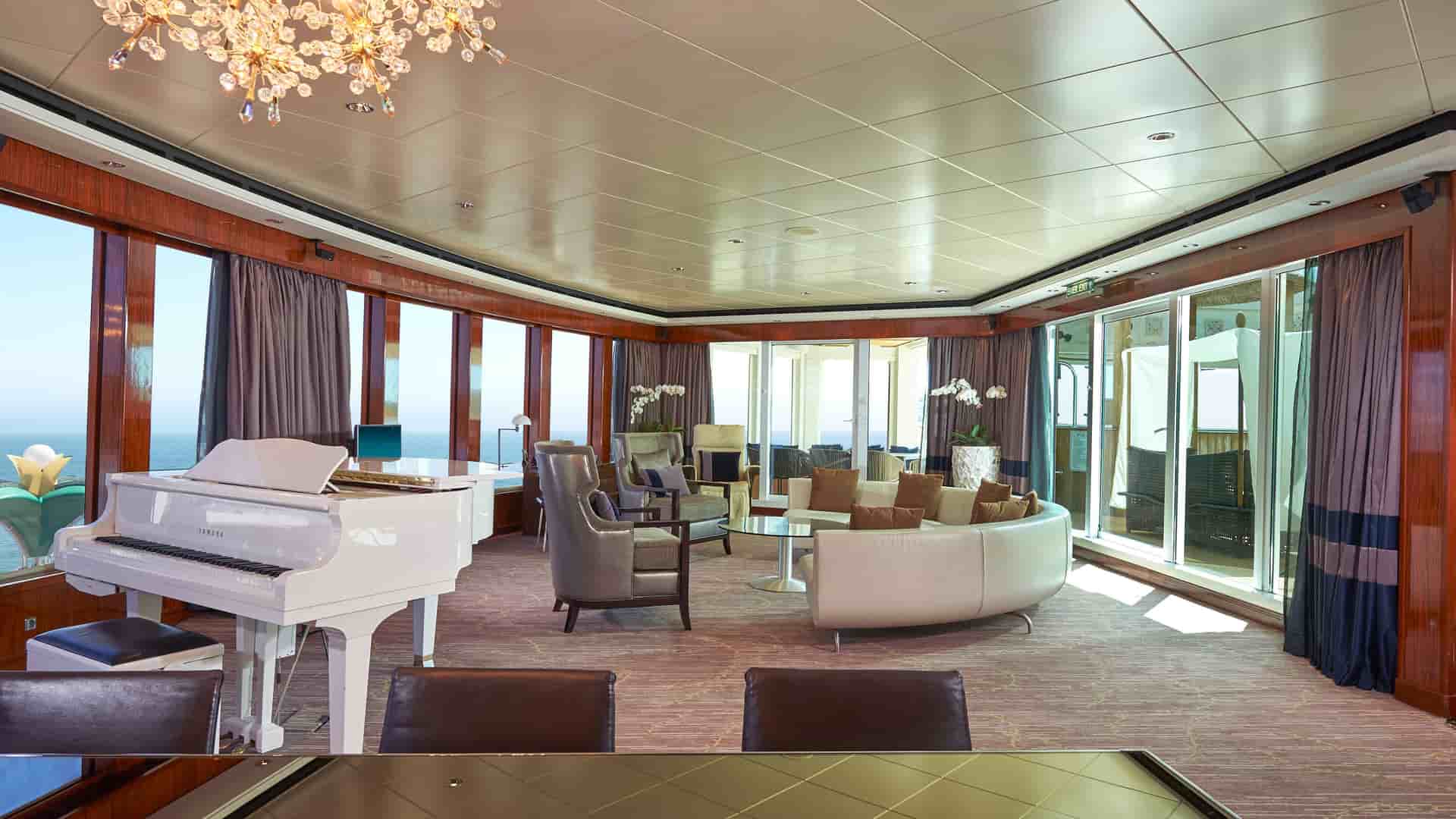 A wide shot image of the living area of a 3 bedroom garden villa aboard Norwegian Cruise Line, showcasing the Grand Piano inside the Haven Suite.