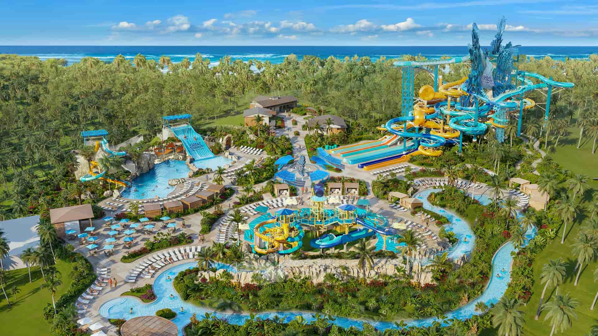 Bird’s-eye view of the Great Tides Waterpark on Norwegian Cruise Line's Great Stirrup Cay, showcasing vibrant water slides, a lazy river, and splash areas surrounded by tropical palm trees and the ocean.
