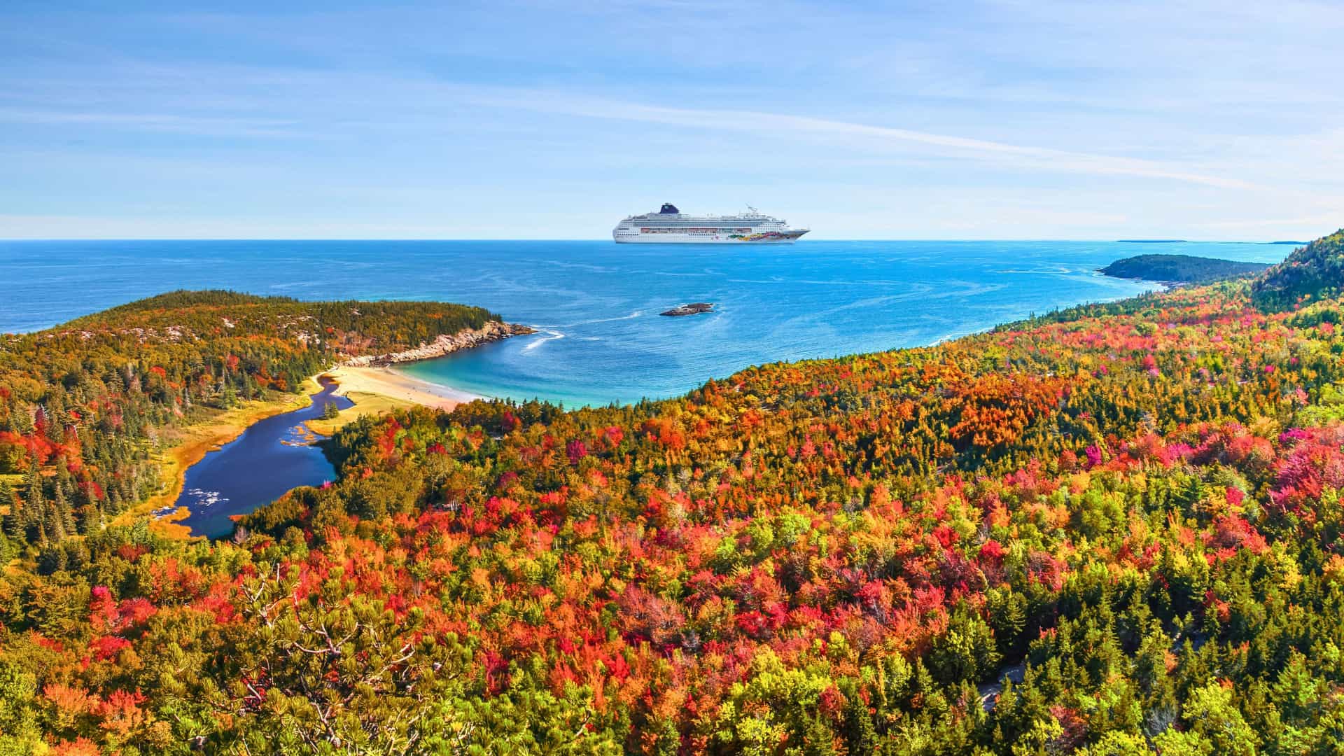 Norwegian Cruise Line ship sailing past the stunning fall foliage of the Canada & New England coastline, offering picturesque autumn views.