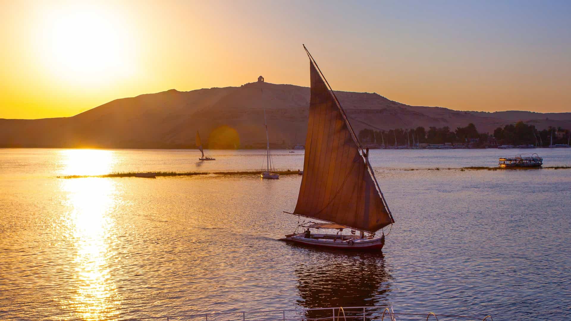 Experience an Oceania Cruises journey along the Nile River in Egypt, featuring a traditional felucca sailboat at sunset.