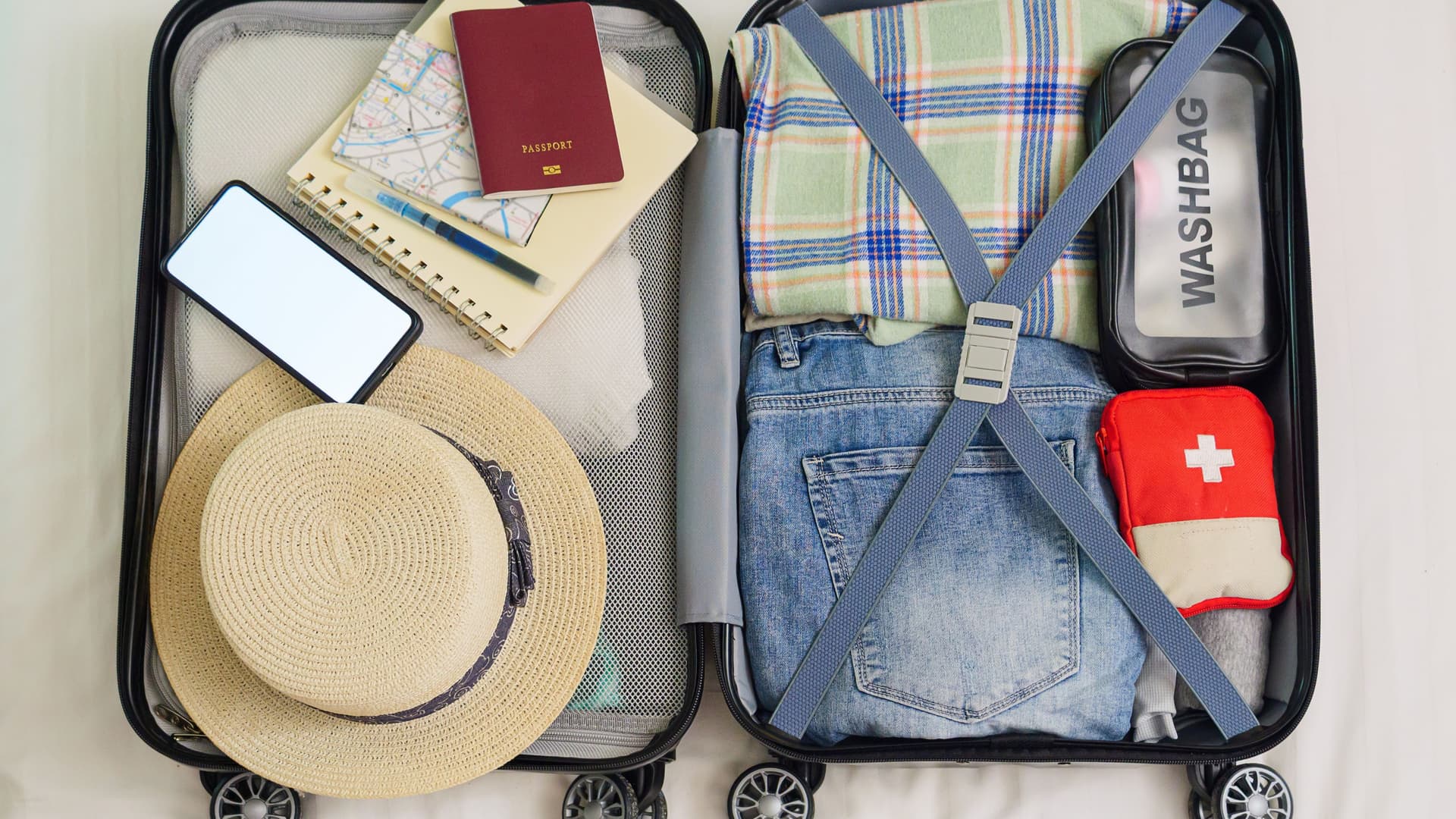 A top down shot of an open suitcase organized with travel essentials.
