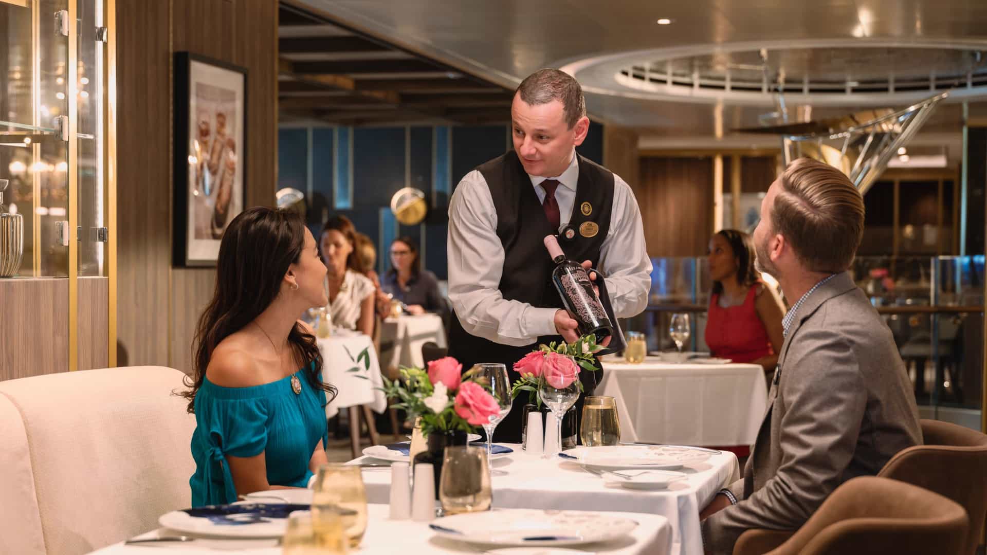 Couple receiving wine service at the Sanctuary Collection fine dining restaurant on Sun Princess.