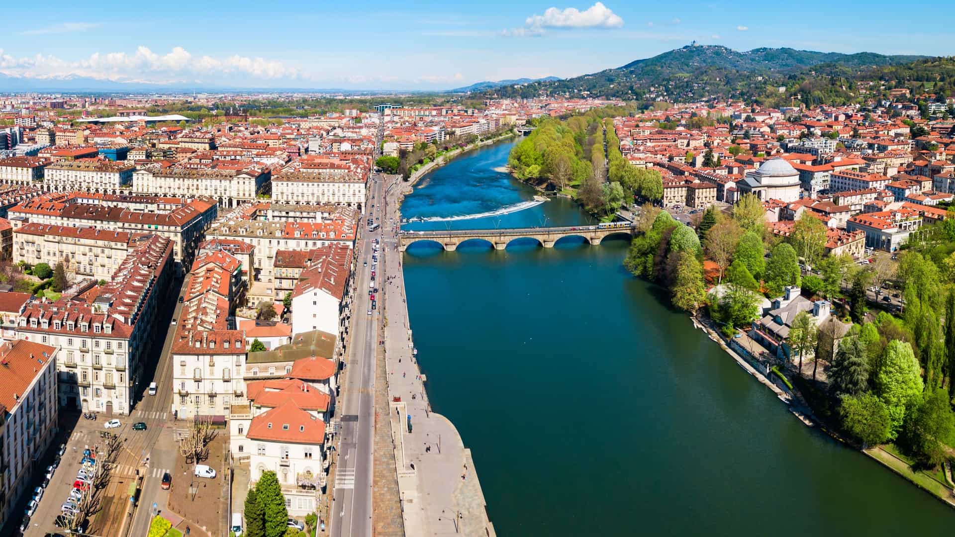 Aerial view of a city featuring the Po River and various buildings along its banks.