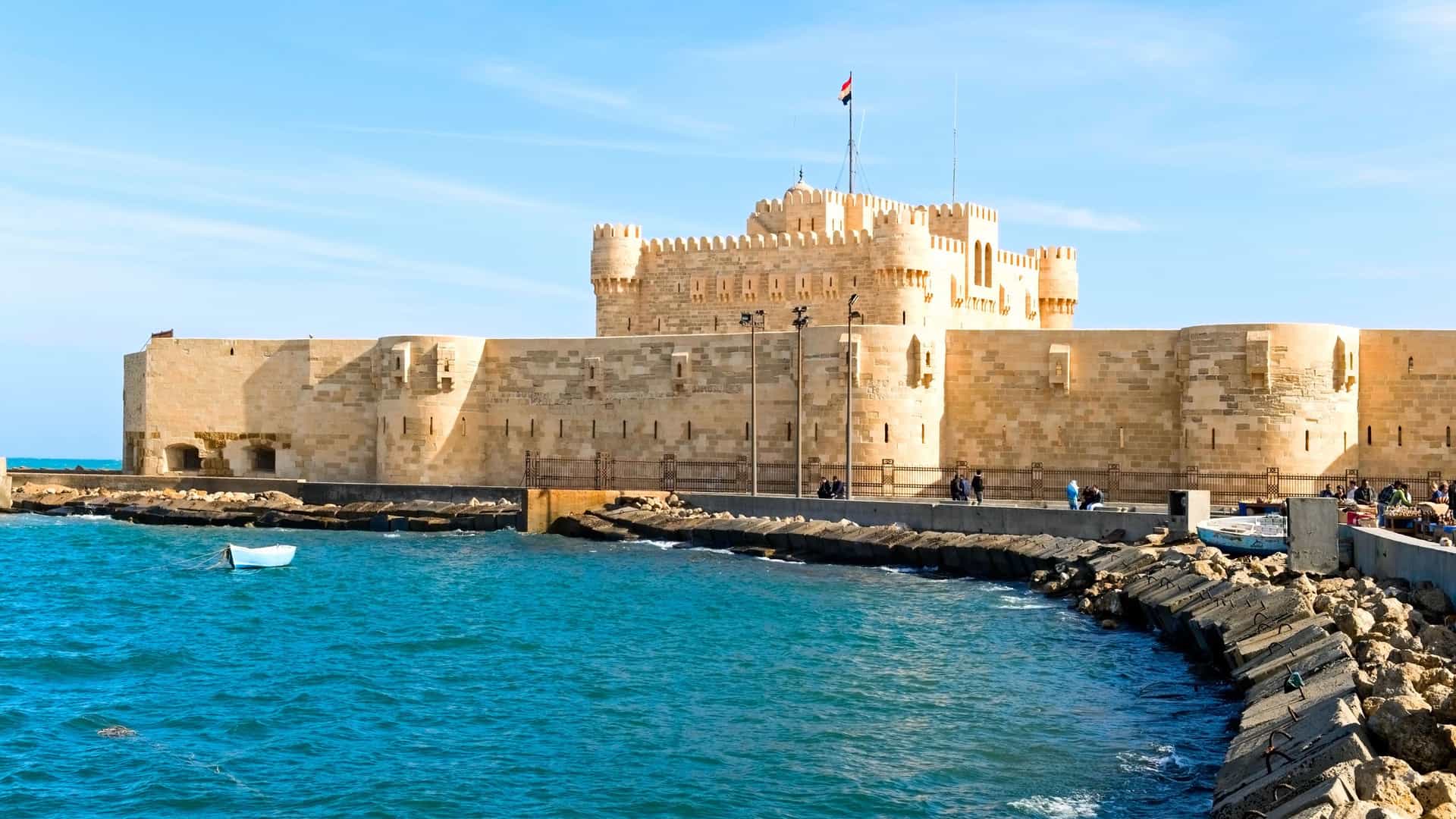 A historic sea fort stands on a rocky promontory overlooking the turquoise water in Alexandria, Egypt.
