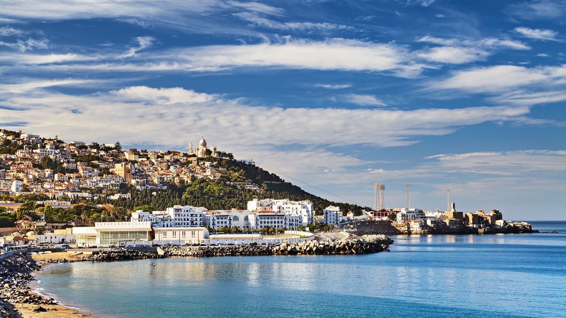 A beautiful view of Algiers, Algeria, with its white buildings built on a steep hill leading down to the deep blue Mediterranean Sea.