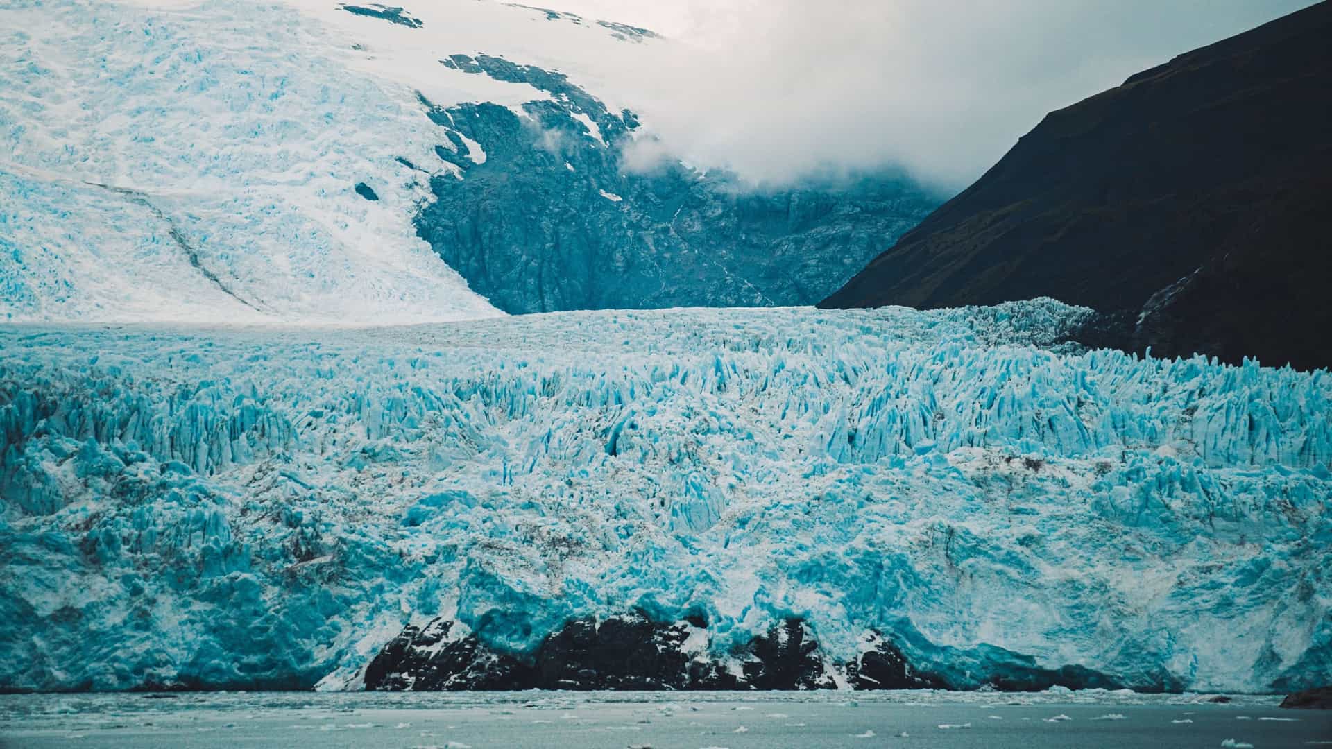 A majestic close-up of the Amalia Glacier's towering, fractured blue ice wall meeting the water, a stunning natural wonder in Chile's Patagonia region.
