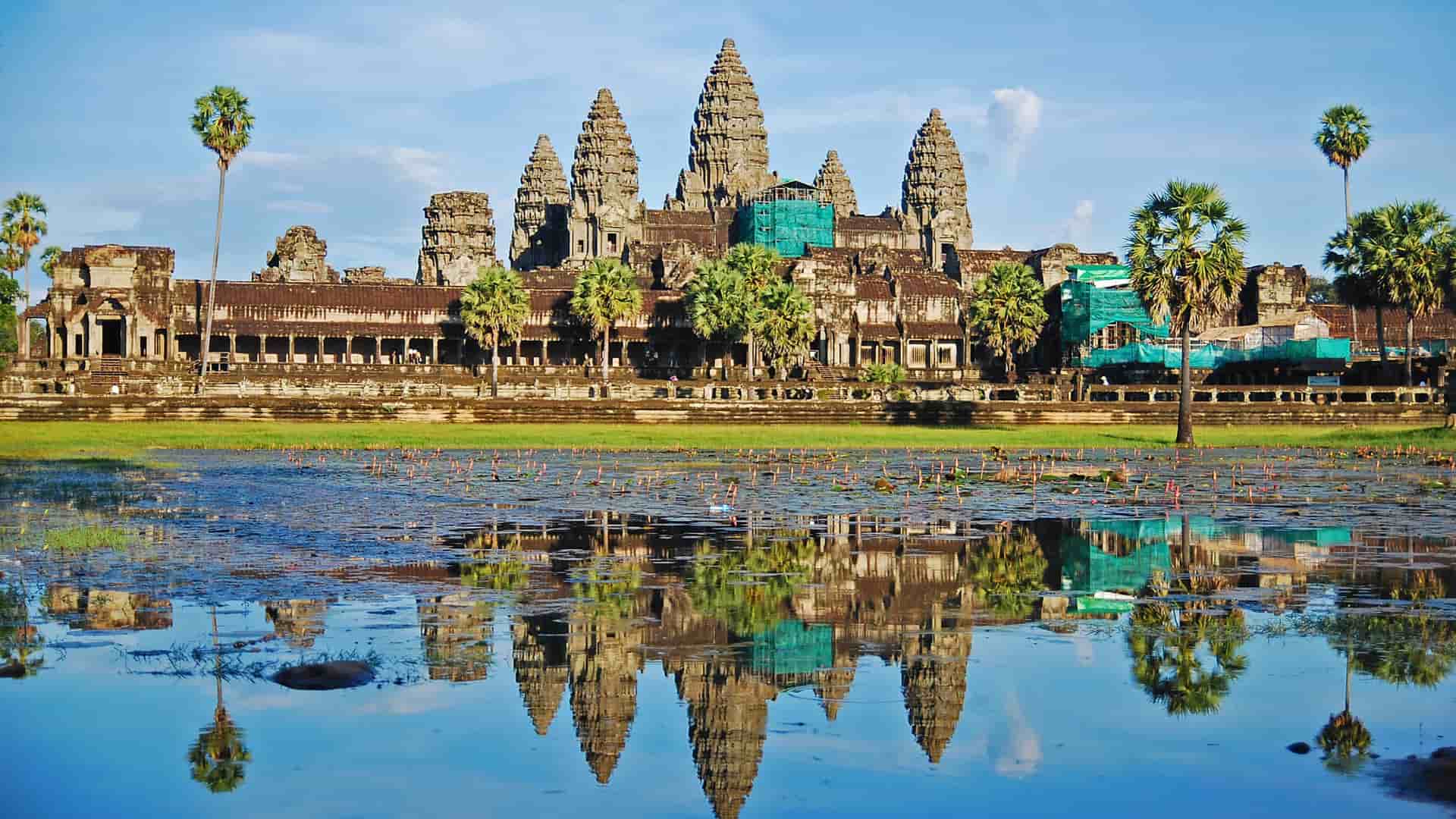 A classic view of the magnificent Angkor Wat temple, a UNESCO World Heritage Site in Cambodia, with its iconic towers reflecting in the water of the surrounding moat.