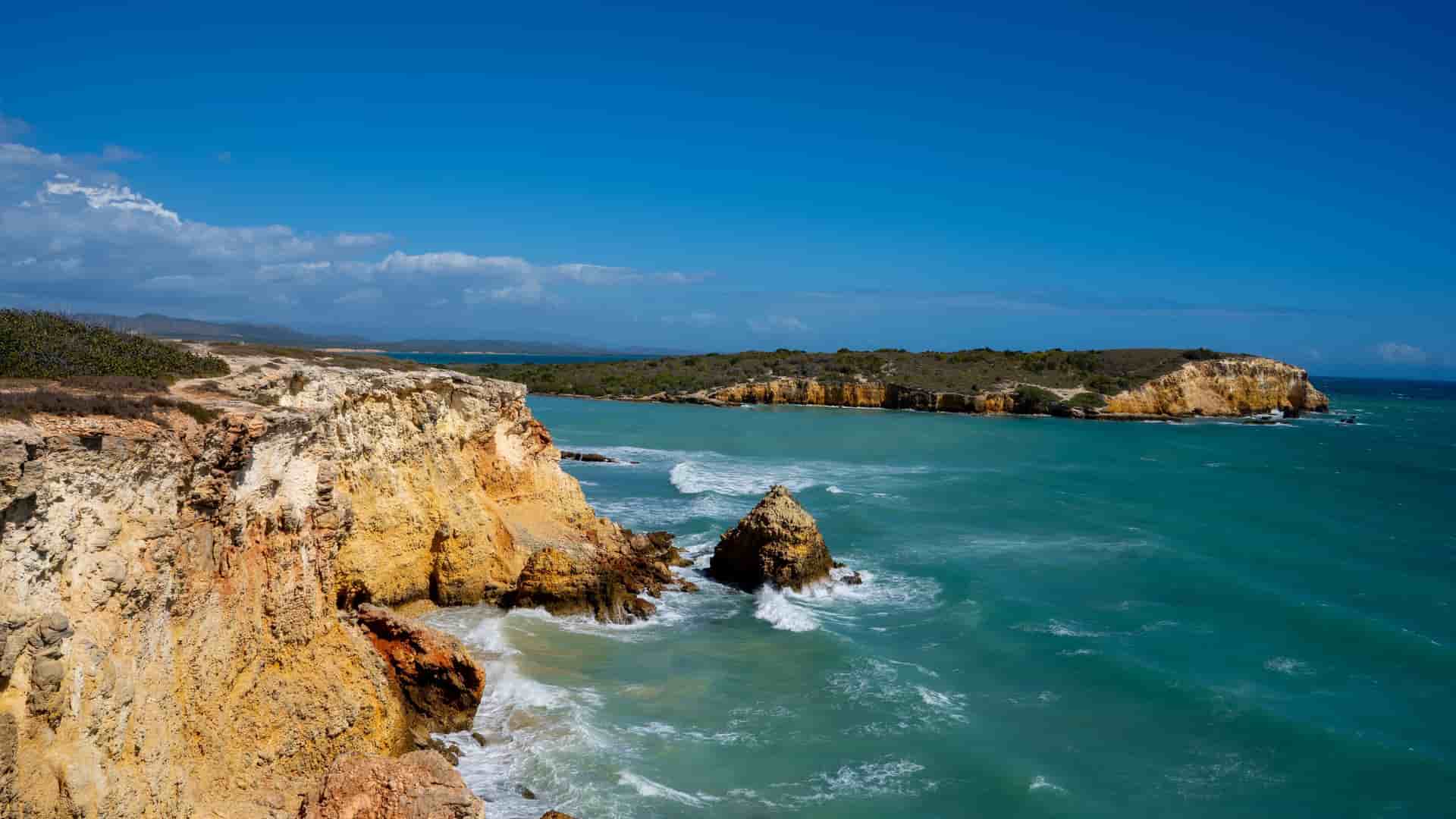 A breathtaking view of the Los Morrillos Lighthouse and the rugged coastline of Cabo Rojo, Puerto Rico, with dramatic cliffs and turquoise water.