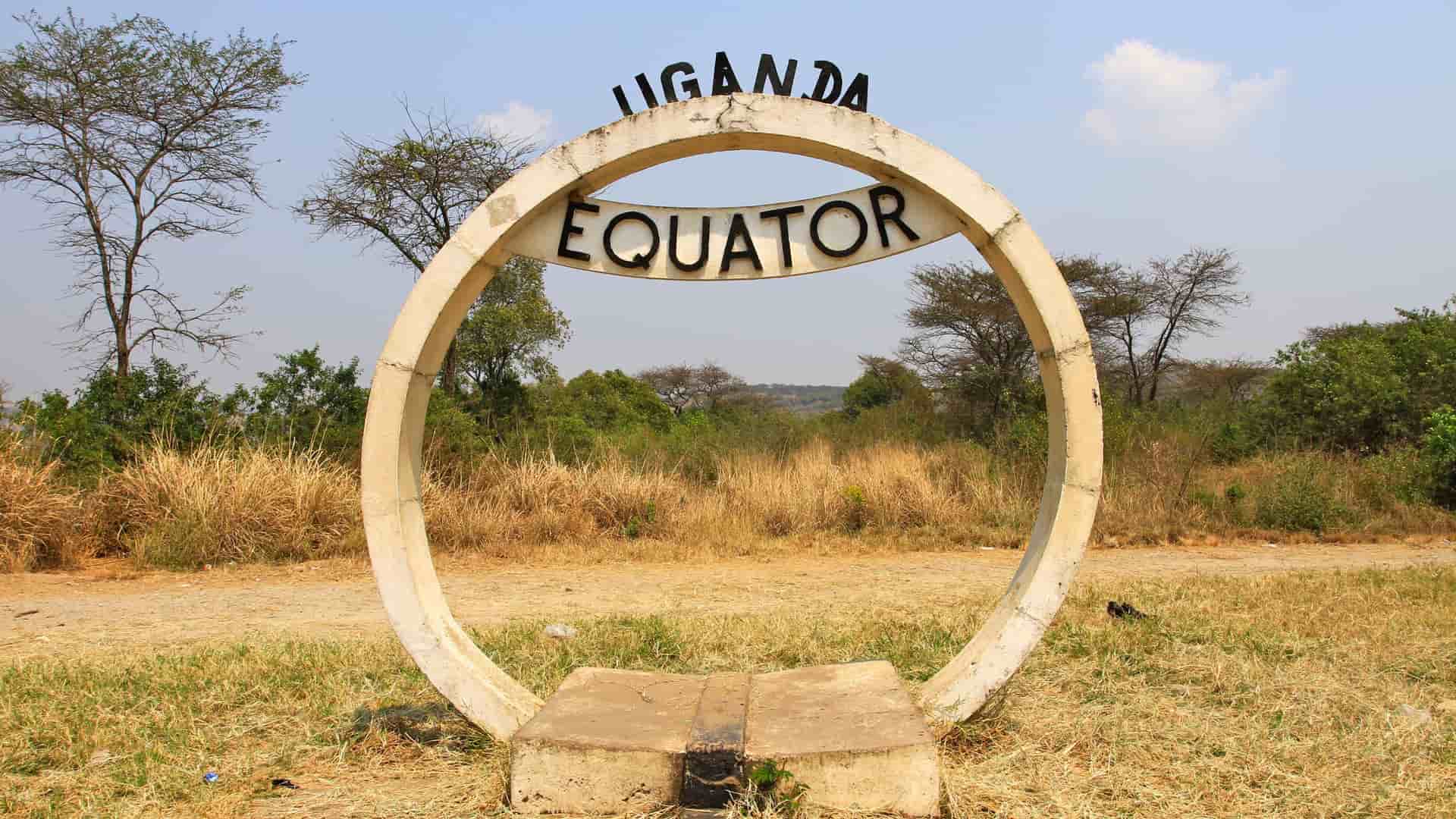 A prominent circular monument marks the Equator in Uganda, featuring the word "EQUATOR" and "UGANDA" with a grassy landscape in the background.