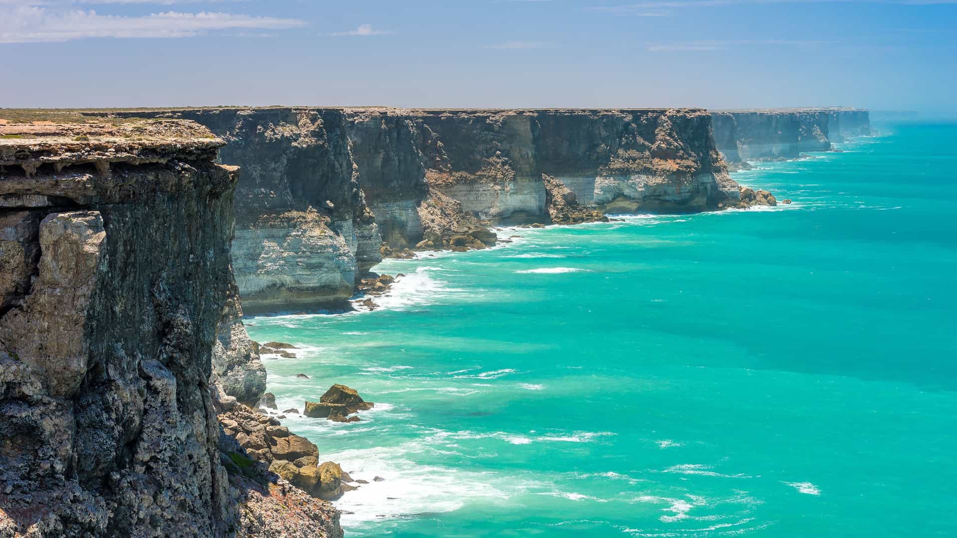A dramatic scenic view of the Bunda Cliffs along the Great Australian Bight, showcasing the rugged coastline and the vibrant turquoise waters of the Southern Ocean.