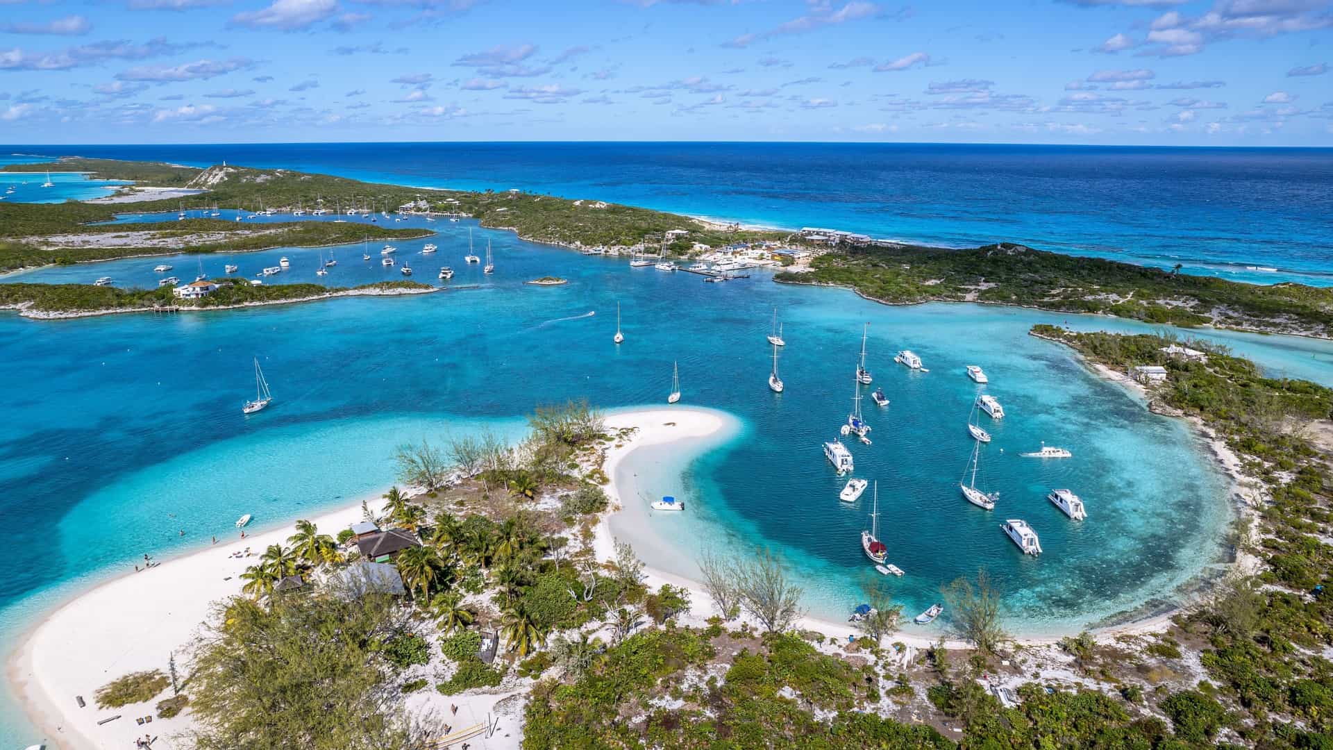 Aerial view of turquoise water, white sand beaches, and sailboats anchored off Great Exuma, The Bahamas.