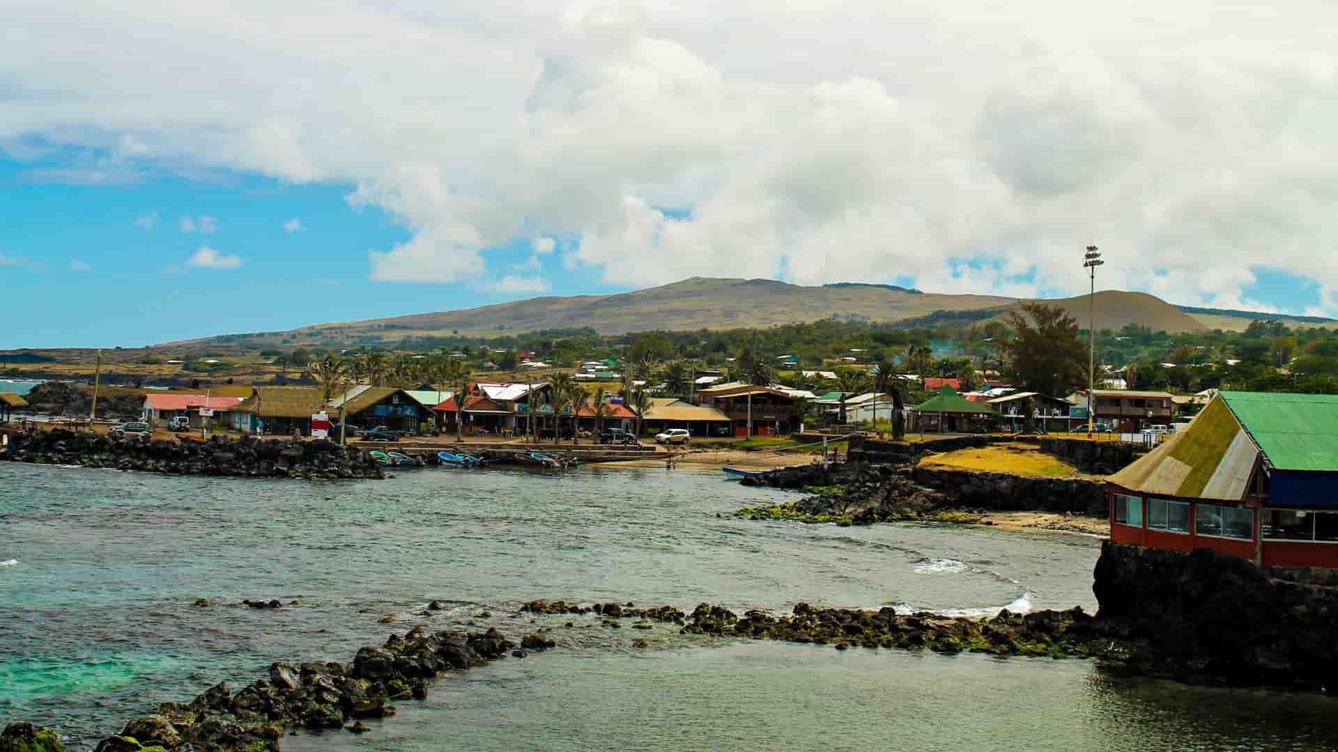 A portrait of a Rapa Nui (Easter Island) woman in Hanga Roa, Chile, possibly wearing traditional Polynesian attire or a flower crown, with the island's volcanic landscape and the Pacific Ocean in the background.