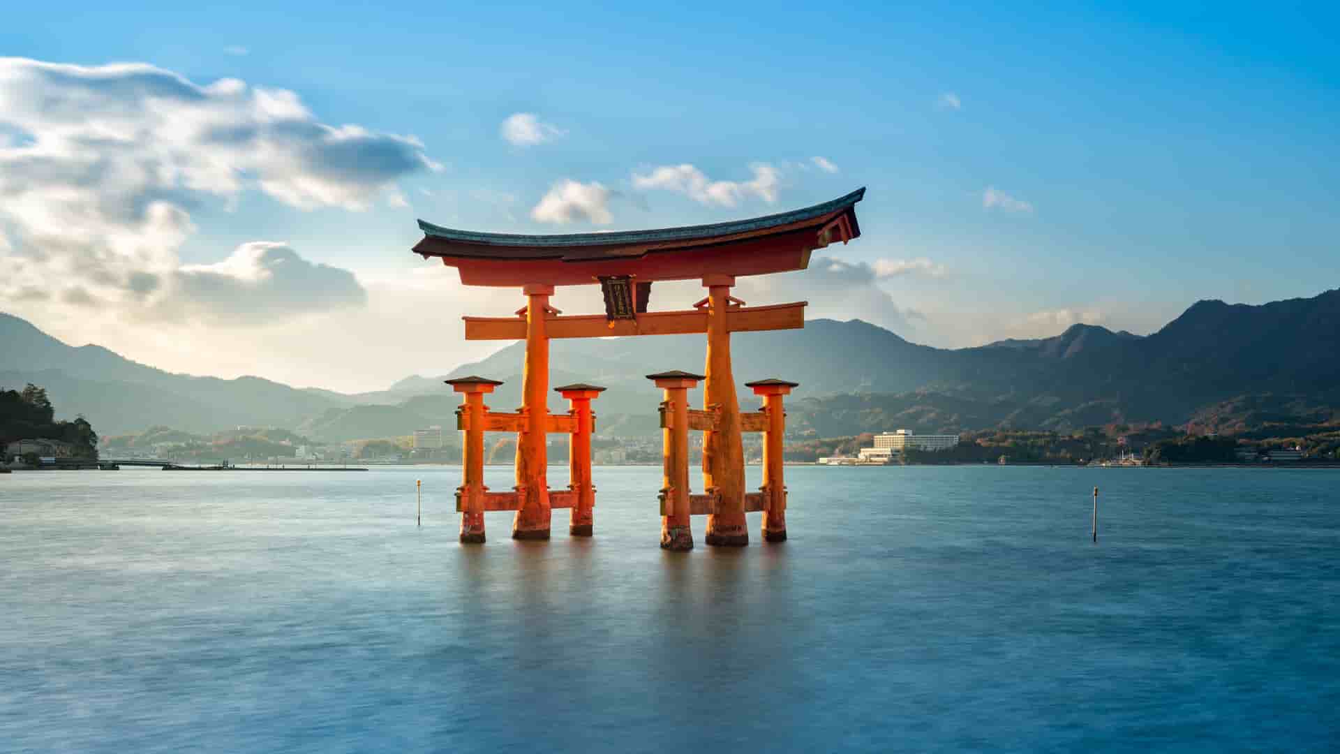 A serene image of the iconic floating Torii gate of the Itsukushima Shrine in Japan, standing in the calm sea with misty mountains in the background.