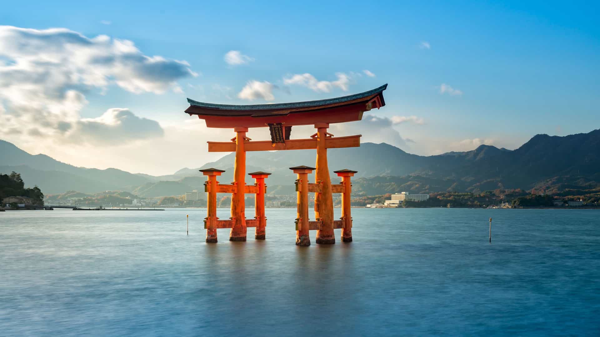 A serene image of the iconic floating Torii gate of the Itsukushima Shrine in Japan, standing in the calm sea with misty mountains in the background.