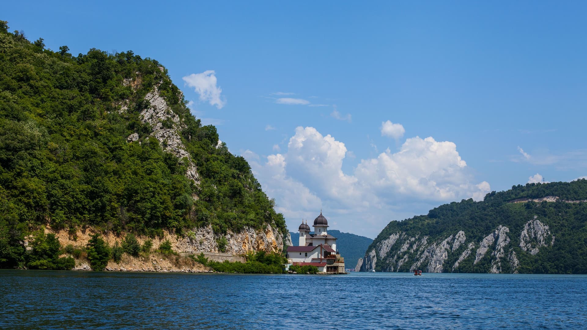A beautiful orthodox monastery, Mănăstirea Mraconia, sits at the base of a forested cliff along the Danube River near the Iron Gates Gorge.