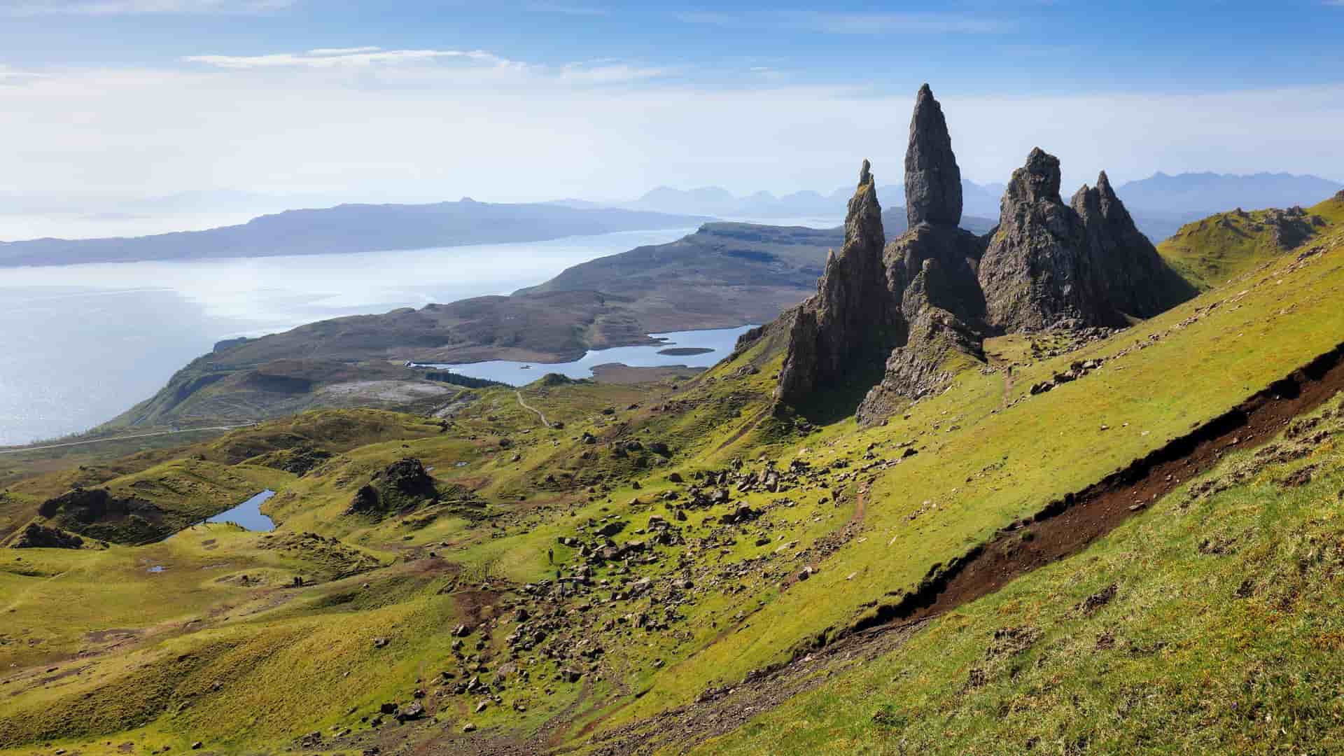 A panoramic view of the iconic Old Man of Storr, a towering rock pinnacle, and the stunning landscape of the Isle of Skye in Scotland.