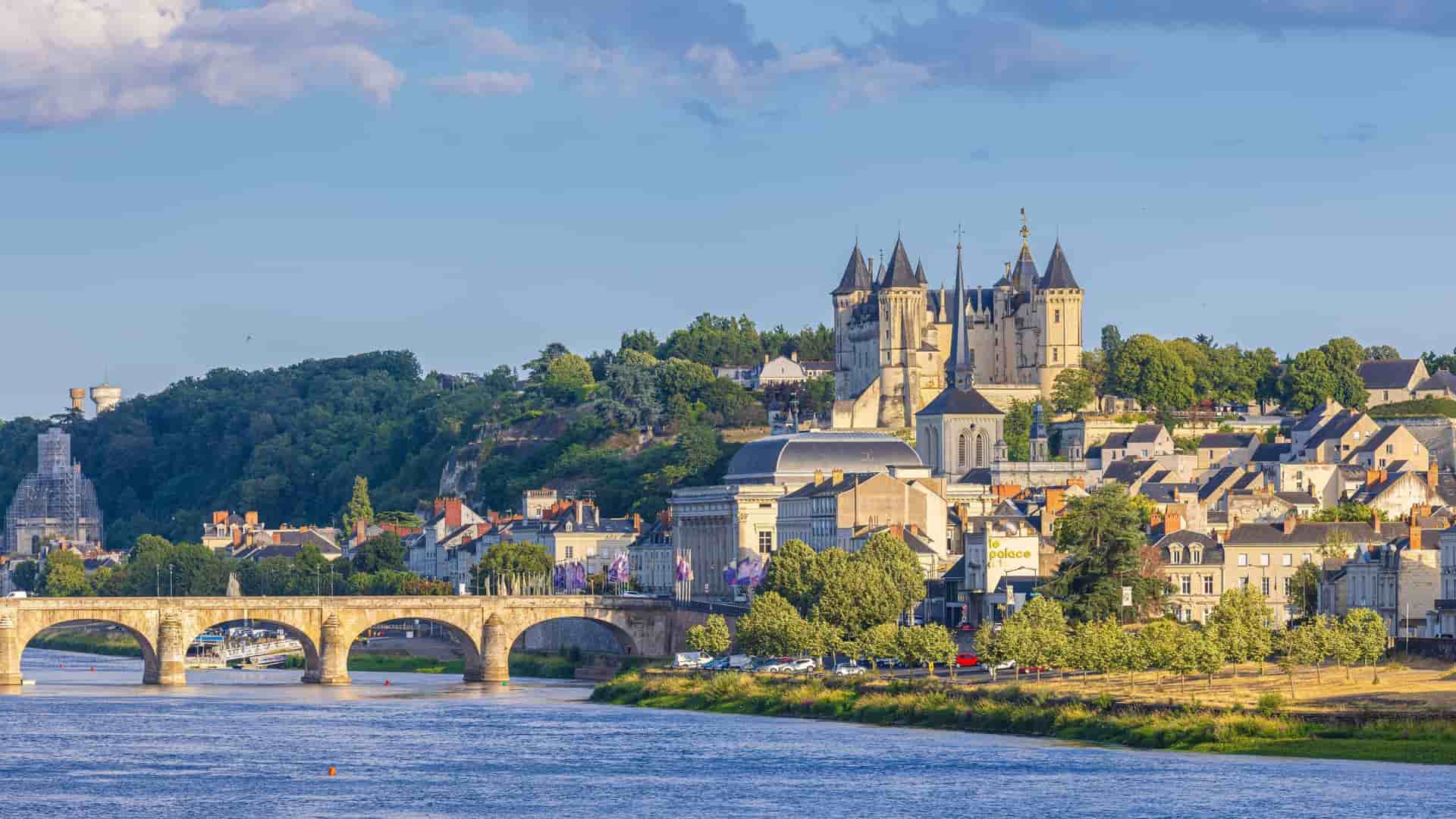 A panoramic shot of Saumur, a charming town in the Loire Valley, France, showing the Chateau de Saumur and a beautiful bridge over the river.