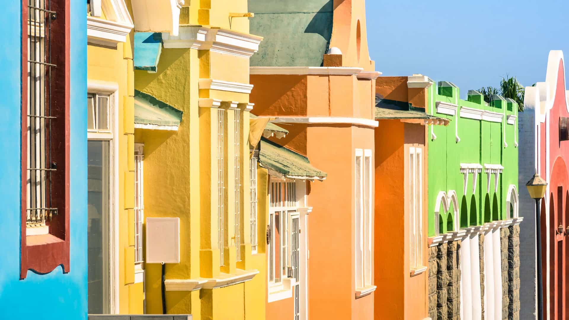 A row of vibrant, brightly colored buildings with German colonial architecture in the coastal town of Luderitz, Namibia.