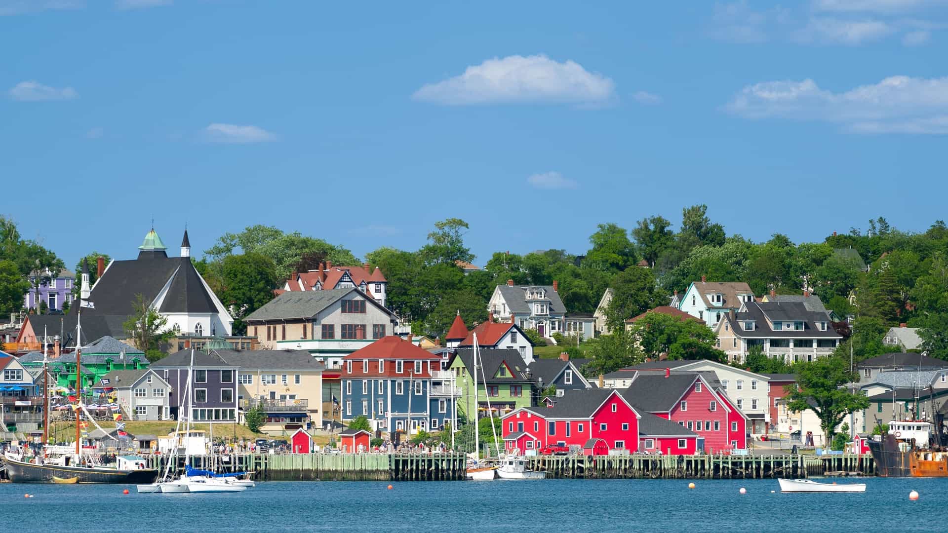 A scenic view of the waterfront in Lunenburg, Nova Scotia, with its colorful historic buildings and charming townscape, a designated UNESCO World Heritage site, on a sunny day.