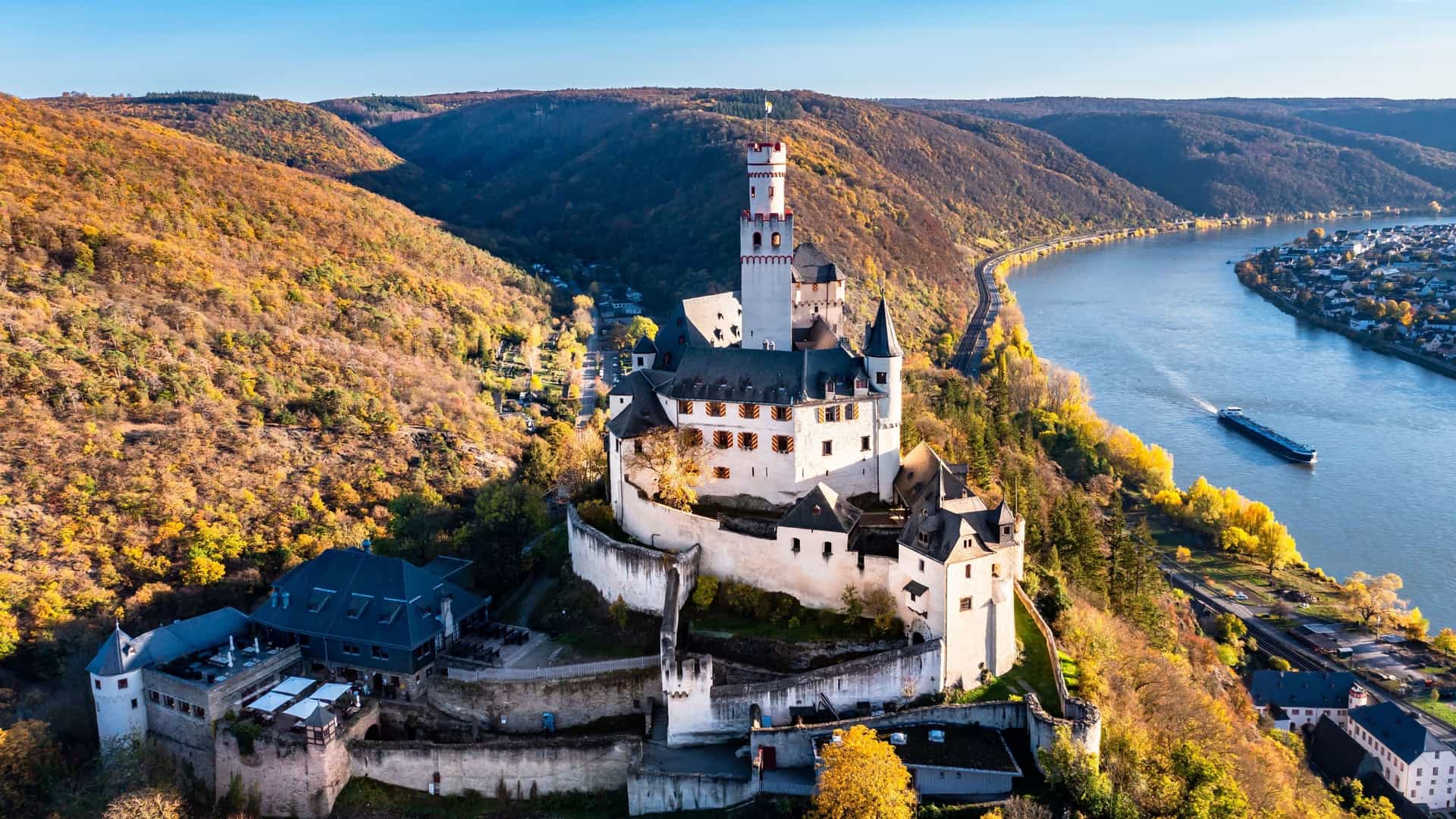 An aerial view of the medieval Marksburg Castle, a historic fortress overlooking the Rhine River and the scenic town of Braubach, Germany.