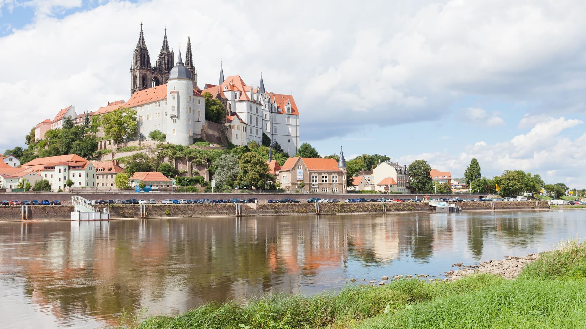 A wide-angle view of the historic Albrechtsburg Castle and the Meissen Cathedral, located on a hill overlooking the Elbe River in Meissen, Germany.