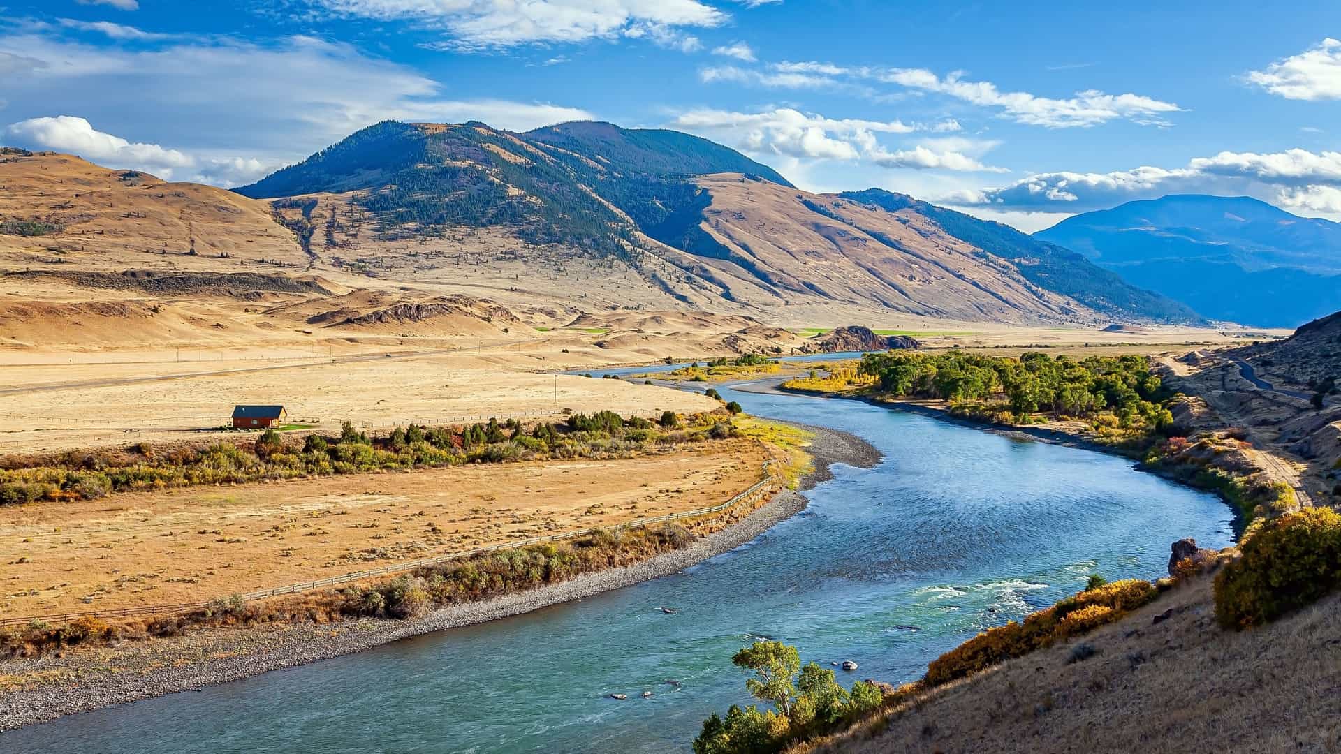 A beautiful and wide scenic view of the Mississippi River winding through a vast valley, surrounded by majestic mountains and rugged landscapes under a bright blue sky.